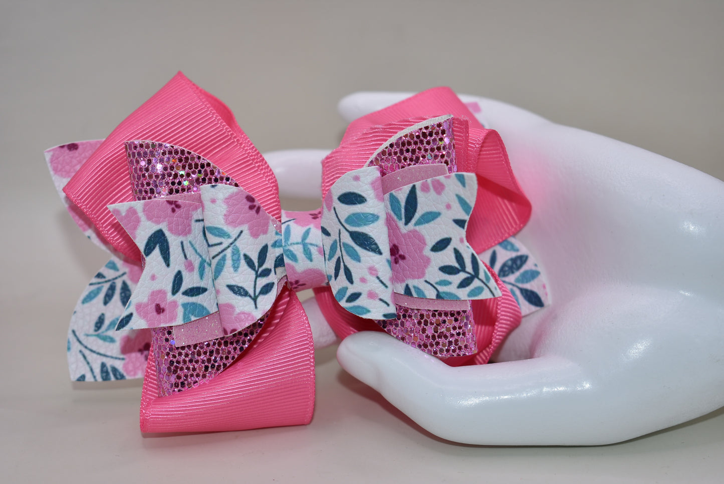 The Bow Corner is a must-have accessory for any little girl! The beautiful 4" pink bow, with its mix of ribbon, glitter, and faux leather, adds a touch of charm to any outfit. The unique flower pattern and covered alligator clip make it both comfortable and easy to wear. (Your little one will look so cute you'll pinkie-swear it!)