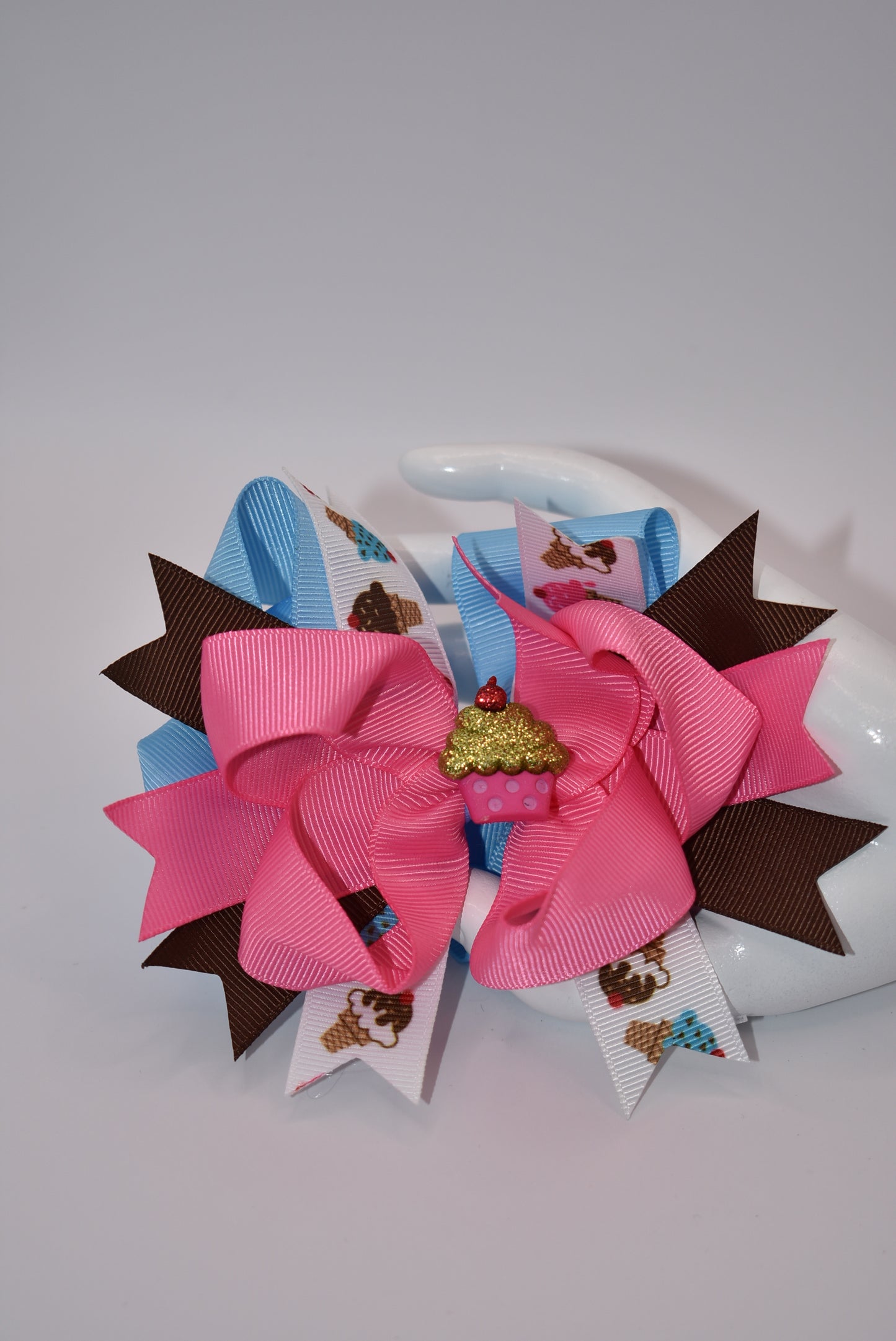 Add some flavor to your little one's style with Nana's Collection! This layered ice cream bow comes in a playful mix of brown, blue, and pink to complement any outfit. The alligator clip makes for easy on and off hair application. It's the perfect blend of fun and function.