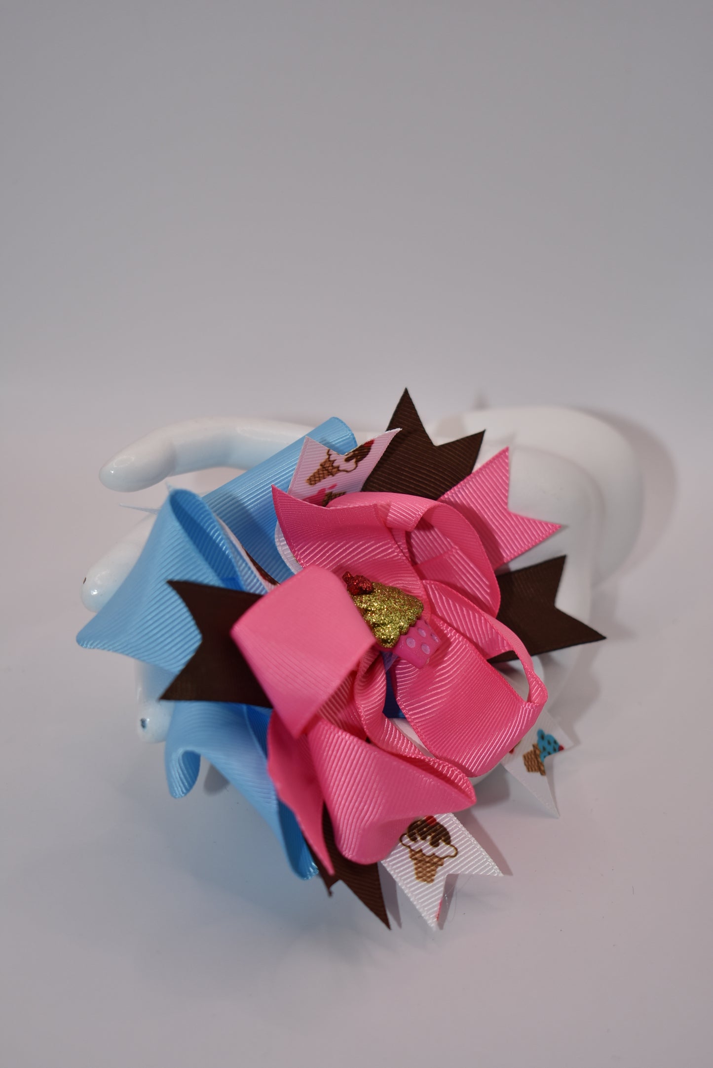 Add some flavor to your little one's style with Nana's Collection! This layered ice cream bow comes in a playful mix of brown, blue, and pink to complement any outfit. The alligator clip makes for easy on and off hair application. It's the perfect blend of fun and function.