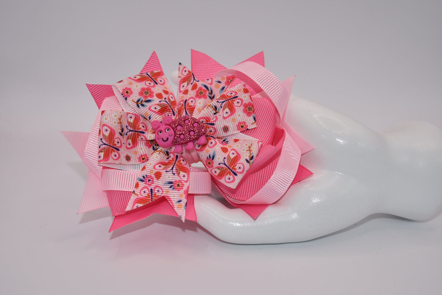 Introducing Nana's Collection - the bow with added cuteness! Adorned with a charming bug on soft pink ribbons, this alligator clip is not only stylish but comfortable too. A one-of-a-kind accessory that will bring smiles (and compliments) wherever you go!