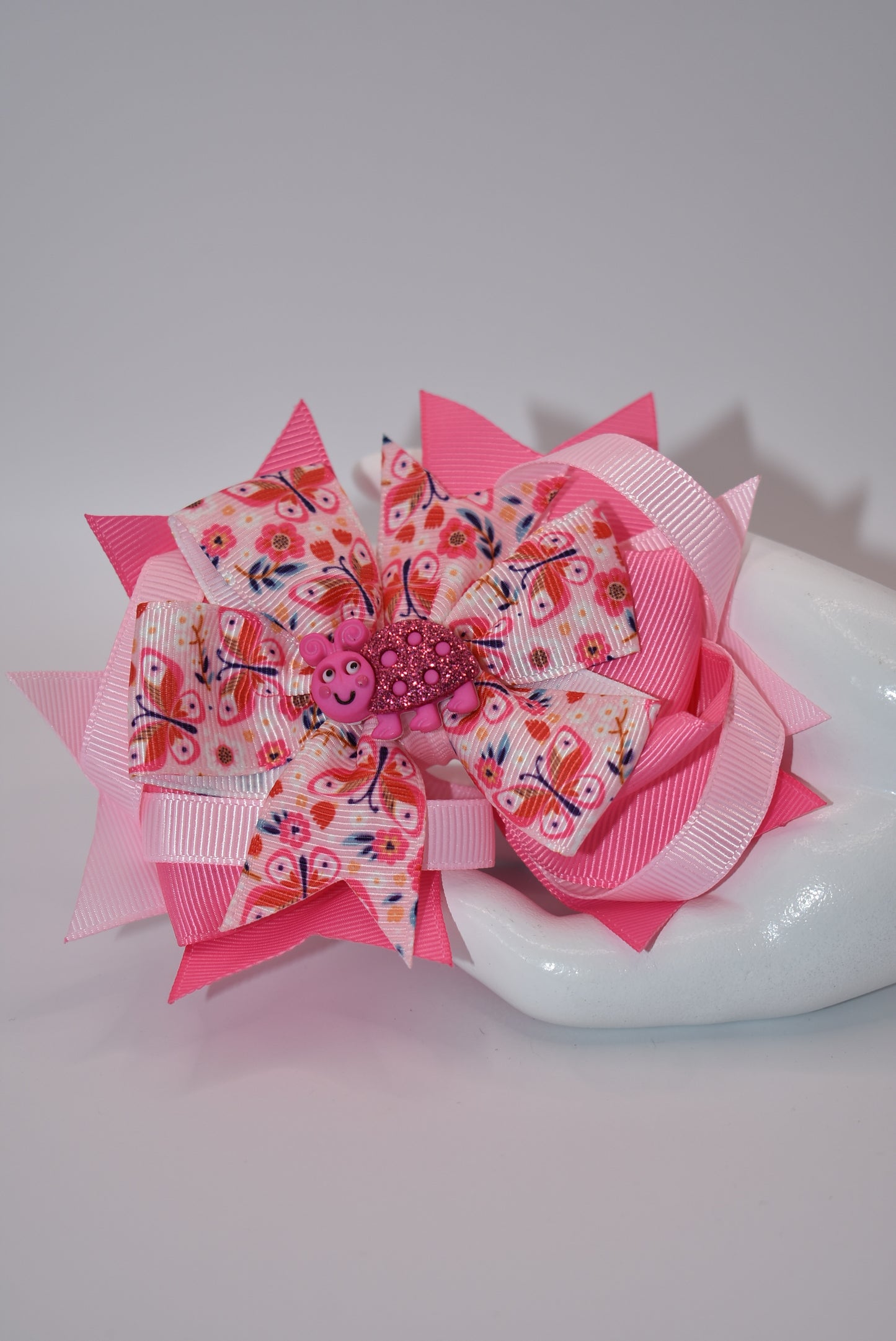 Introducing Nana's Collection - the bow with added cuteness! Adorned with a charming bug on soft pink ribbons, this alligator clip is not only stylish but comfortable too. A one-of-a-kind accessory that will bring smiles (and compliments) wherever you go!