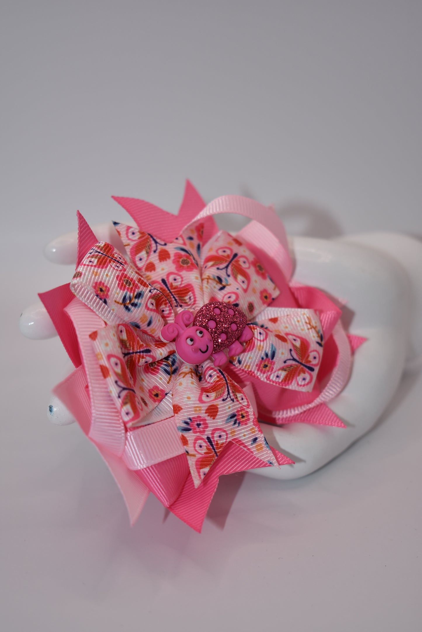 Introducing Nana's Collection - the bow with added cuteness! Adorned with a charming bug on soft pink ribbons, this alligator clip is not only stylish but comfortable too. A one-of-a-kind accessory that will bring smiles (and compliments) wherever you go!