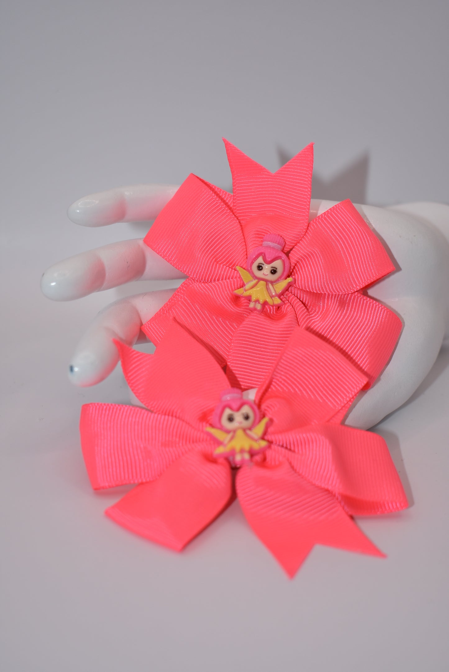 Add a touch of whimsy to your little girl's pigtails with Nana's Collection! This set of two pretty pink bows features adorable fairy designs on top to keep her safe. Plus, the alligator clip ensures a secure fit. Perfect for any playful princess!