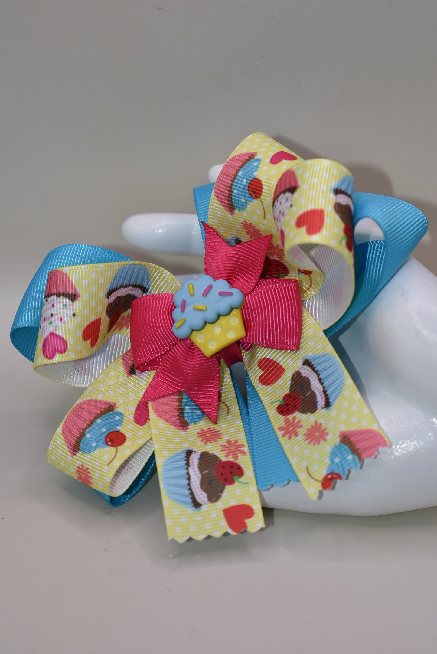 Indulge in Nana's Collection 71, featuring a playful bow with an adorable cupcake charm. The covered alligator clip makes for easy wear, perfect for any occasion. Satisfy your sweet tooth with this fun and quirky cupcake