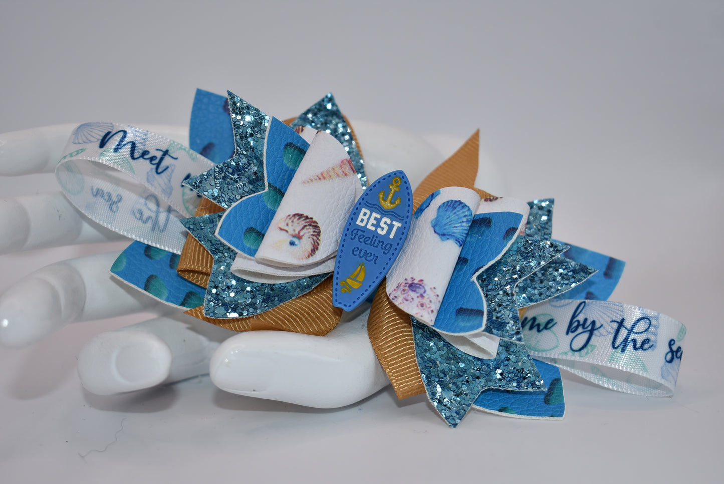 Catch some wave-ready style with Nana's Collection. This faux leather bow features a ribbon and glistening surfboard charm for a playful touch. Securely clipped in place, this one-of-a-kind accessory will make them say "Seas the day!" (Only 1 exclamation point)