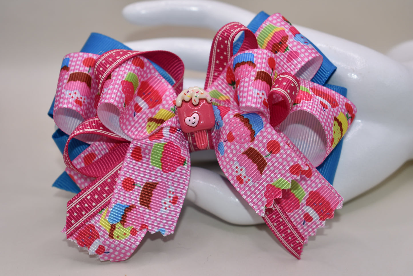 Add a splash of fun with this adorable cupcake ribbon bow, wrapped in bright, multi-colored grosgrain ribbons! 🧁✨ The cutest little charm tops it off, making it perfect for any playful outfit. Finished with a wrapped alligator clip on the back for easy wear and secure hold. 🎀💖 Perfect for adding a sweet touch to your day!