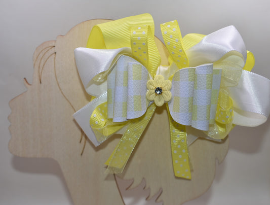 Add a splash of sunshine to your look with this playful hair clip from Nana's Collection 166. Featuring a cheerful mix of yellow and white ribbons accented with charming polka dots, it’s topped with a cute yellow flower and sparkling crystal for a touch of sparkle. The wrapped alligator clip ensures a secure hold, making it perfect for brightening any hairstyle with a fun, whimsical flair.