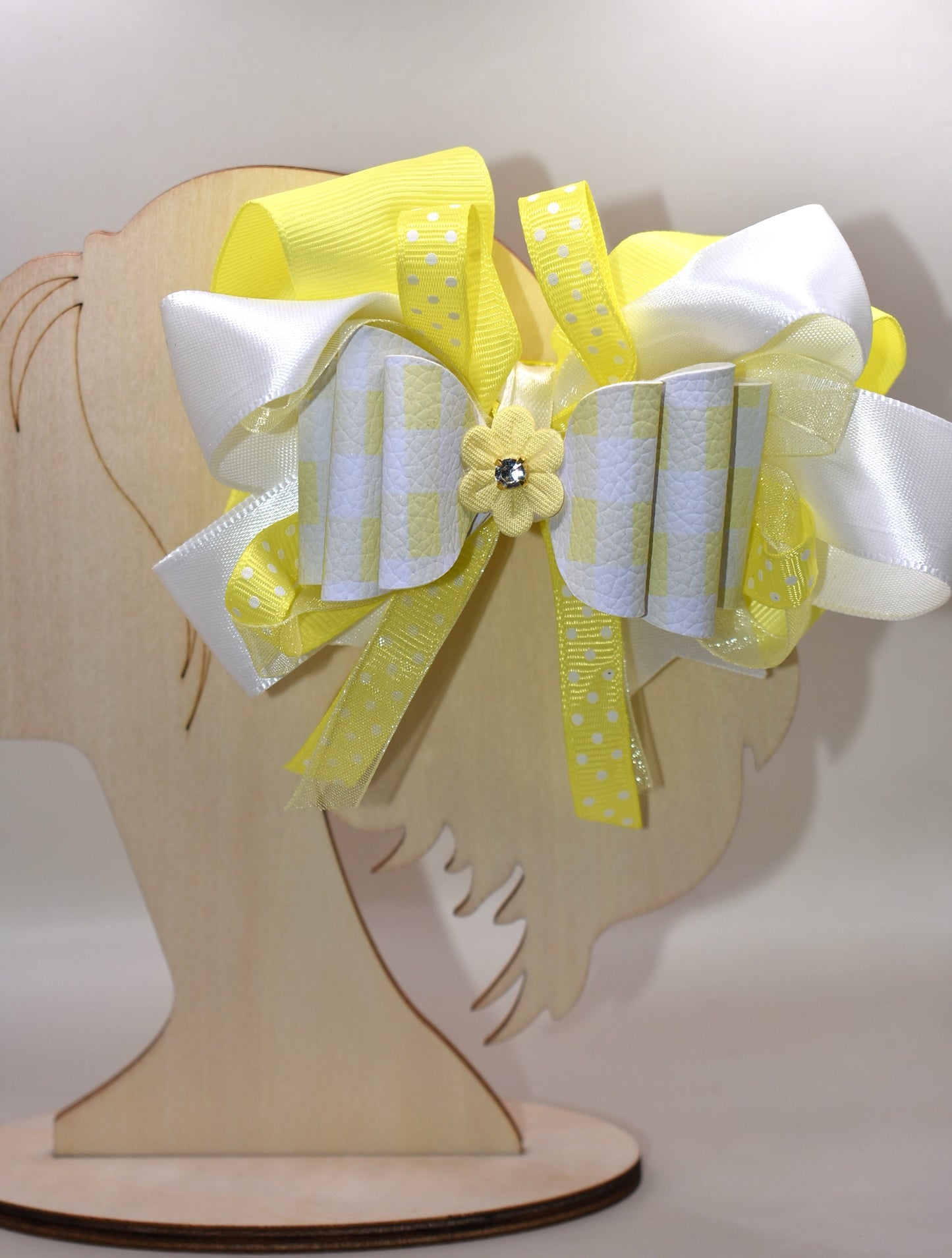 Add a splash of sunshine to your look with this playful hair clip from Nana's Collection 166. Featuring a cheerful mix of yellow and white ribbons accented with charming polka dots, it’s topped with a cute yellow flower and sparkling crystal for a touch of sparkle. The wrapped alligator clip ensures a secure hold, making it perfect for brightening any hairstyle with a fun, whimsical flair.