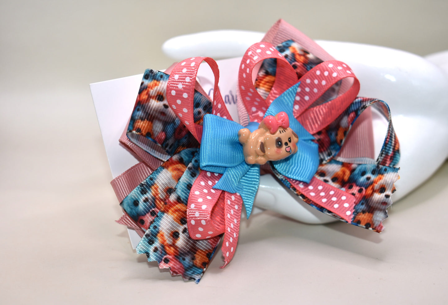Add a splash of fun with this adorable dog charm from Nana's Collection! Featuring layers of a cute pup and a cheerful polka dot ribbon, it clips on easily with a wrapped alligator clip—perfect for quick, playful style. 🐶🎀 Clip it on and let the smiles begin!