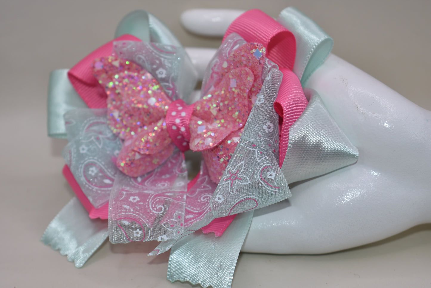 Add a touch of magic with this glittery butterfly perched atop a delicate mint green and pink ribbon. The comfy alligator clip keeps it secure, making it perfect for your little one to wear all day. Pretty, elegant, and absolutely adorable—watch her fall in love and never want to take it off! 🦋💚🎀