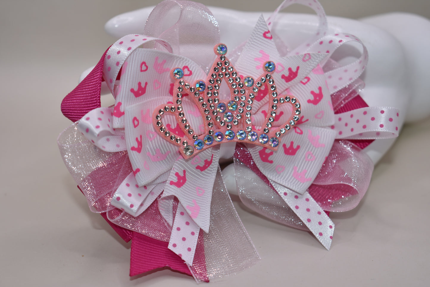 Add a touch of magic with this perfect pink princess bow! 🎀 Layers of ribbon featuring a charming princess motif come together topped with a sparkling pink glitter crown 👑. This one-of-a-kind bow clips securely with an alligator wrapped clip, making it a delightful accessory for any little princess. ✨