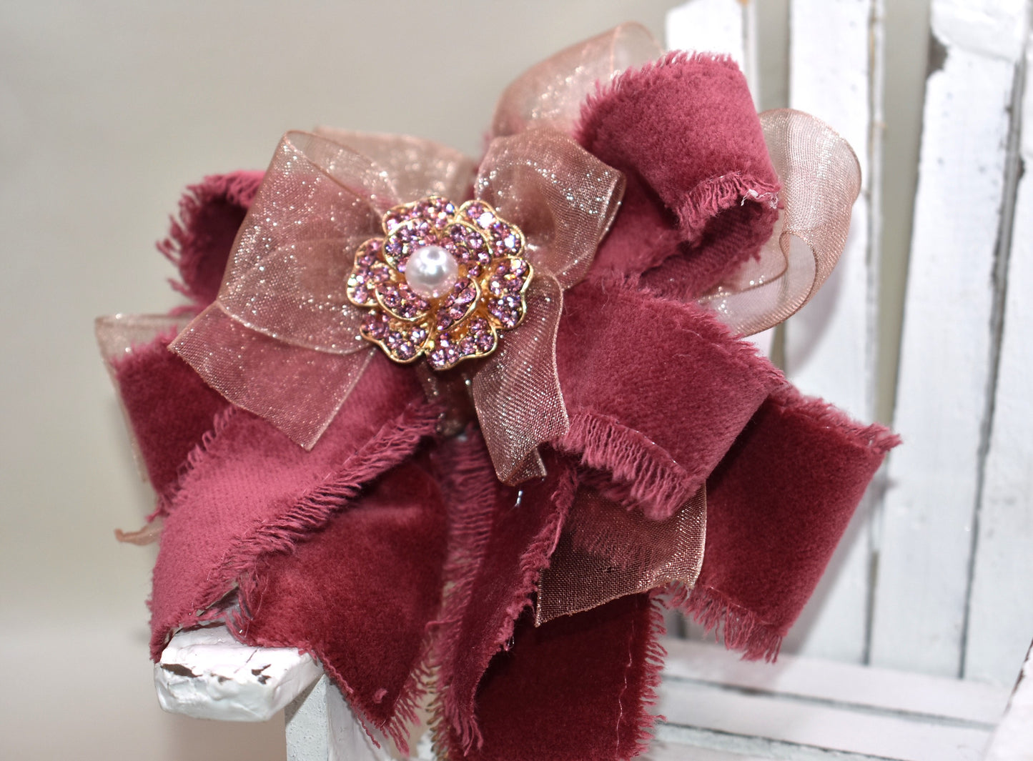 Add a playful pop of color with this gorgeous burgundy velour ribbon accented by soft pink organza. Perfect for dressing up a special outfit for you or your little one, it features a wrapped alligator clip for secure, all-day wear. A sparkling pink rhinestone and pearl piece crowns the top, tying the whole look together with charming sparkle.
