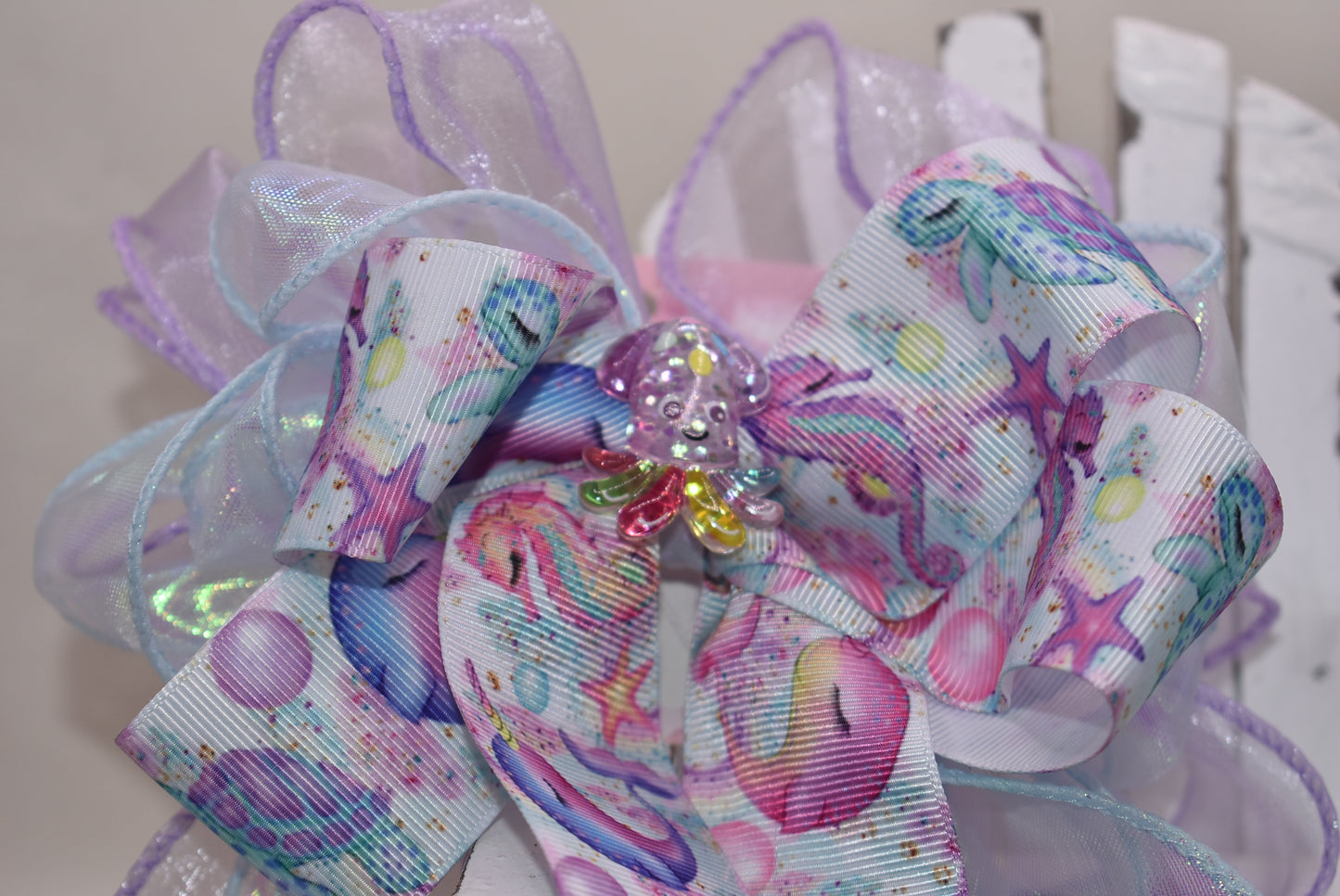 Make a splash with this playful nautical-themed long bow! Layers of beautiful ribbon cascade gracefully, topped with the cutest octopus charm 🐙 for an adorable touch. Featuring a French barrette clip with a snap-on closure, it ensures a perfect fit for any hair adventure. Perfect for adding a sea-inspired charm to your look! ⚓🌊