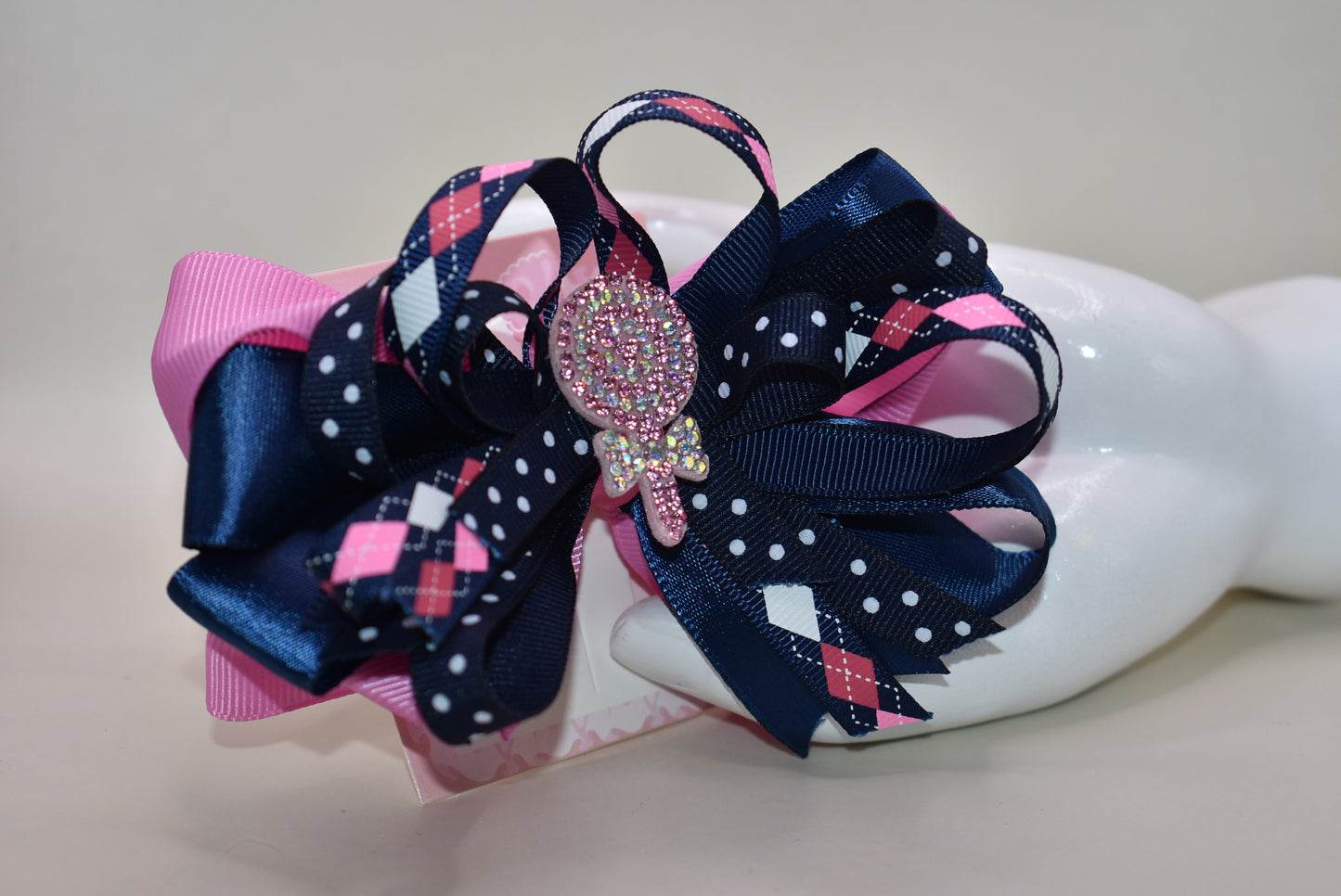Add a pop of fun with this playful bow from Nana's Collection! Layers of pretty blue and pink ribbons create a charming swirl topped with a sparkling candy embellishment that’s sure to catch the eye 🍬✨. Perfect for adding a little extra sparkle to any outfit, it stays put all day thanks to a handy wrapped alligator clip. Sweet style made easy! 🎀