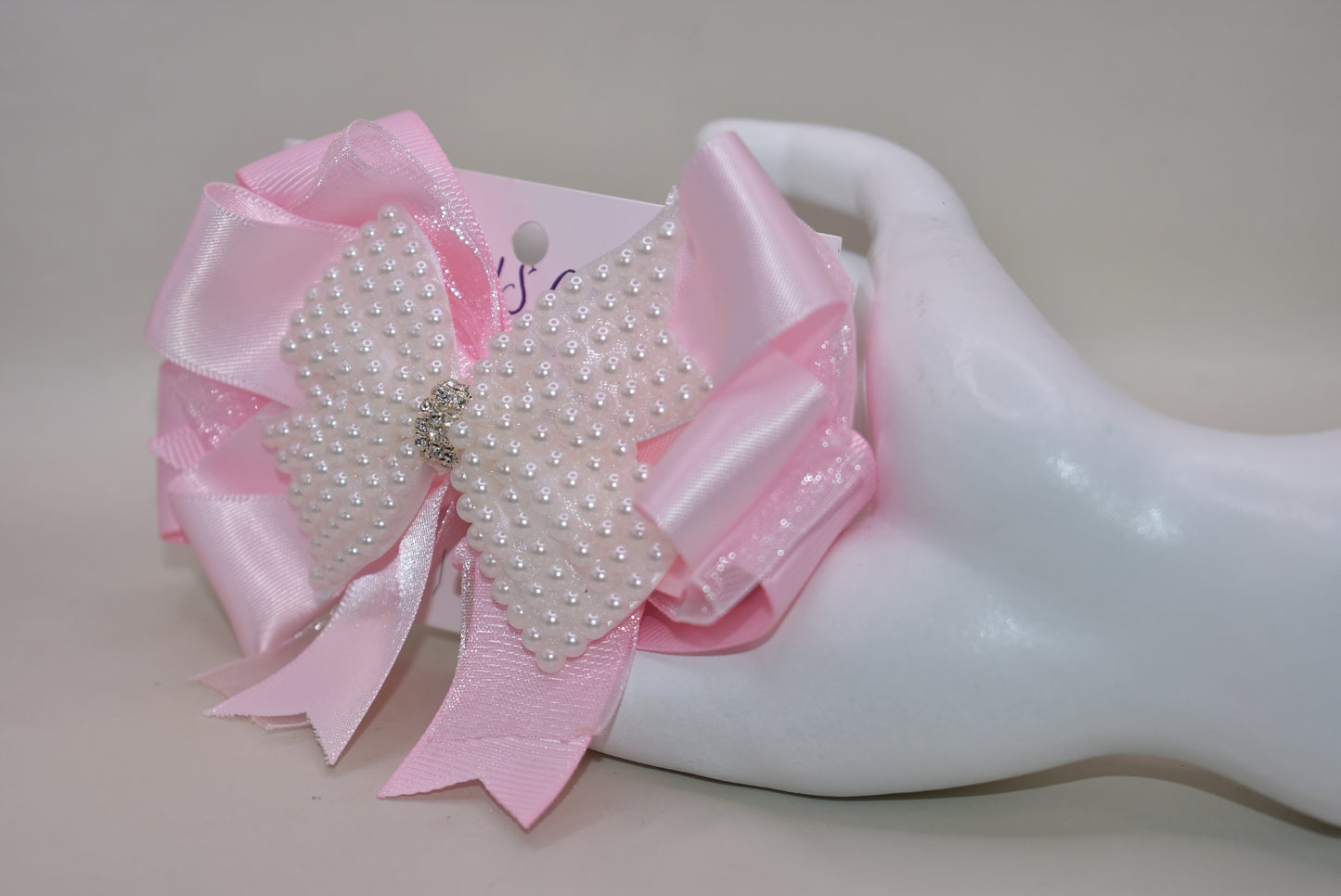 Add a splash of charm with this beautiful pink bow from Nana's Collection! 🌸 Layers of soft pink ribbons create a perfect princess look, topped with a sparkling pearl and crystal wrap ✨. The wrapped alligator clip makes it super easy to wear all day long. Perfect for the little girl who loves everything pink and pretty! 🎀💕