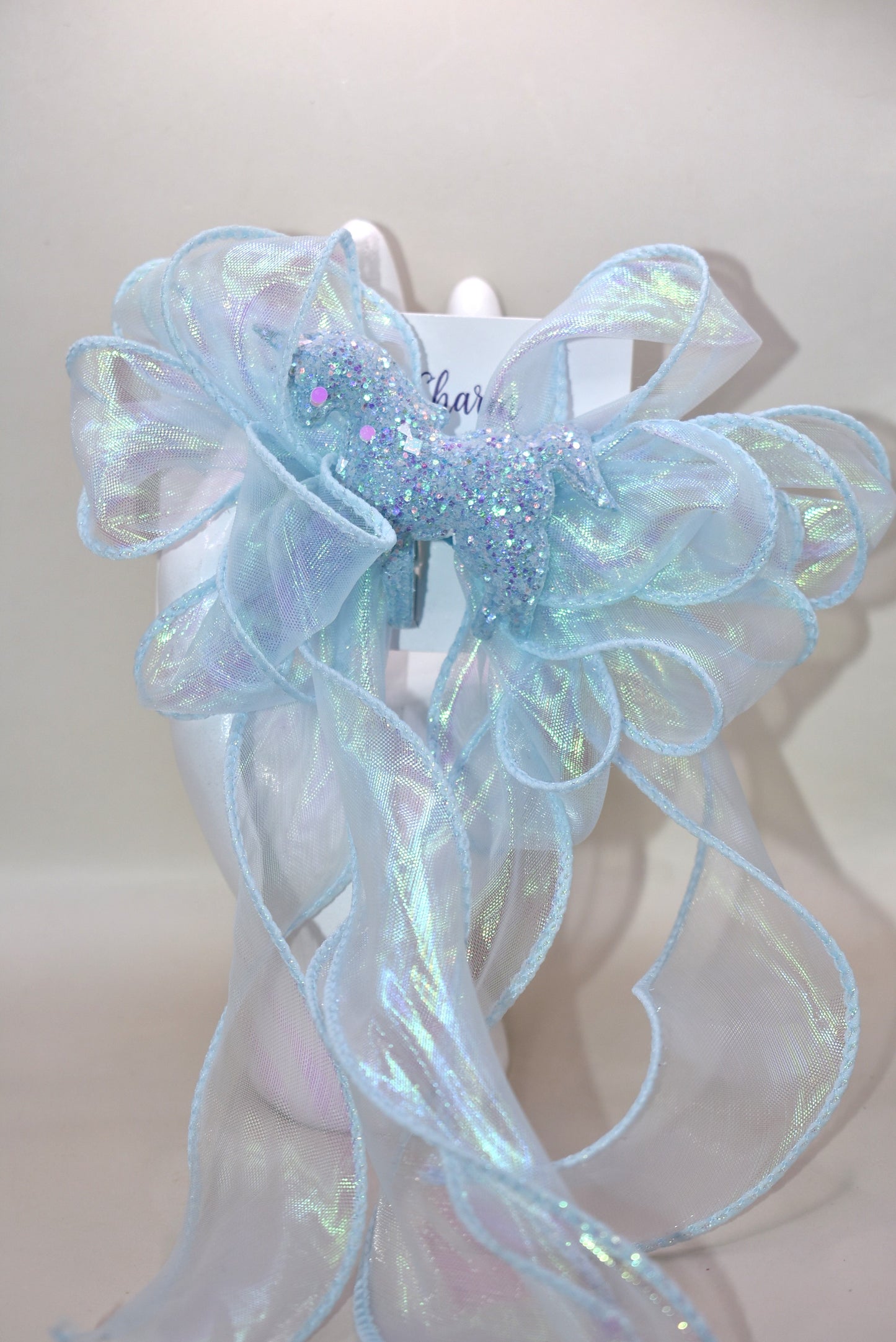 Add a splash of sparkle with this baby blue iridescent fishtail ribbon 🎀, perfectly wrapped on a baby blue alligator clip 🐬. Topping it off is a glittery blue horse 🐴 that brings magic to any outfit! Fun, vibrant, and full of charm—get ready to shine! ✨