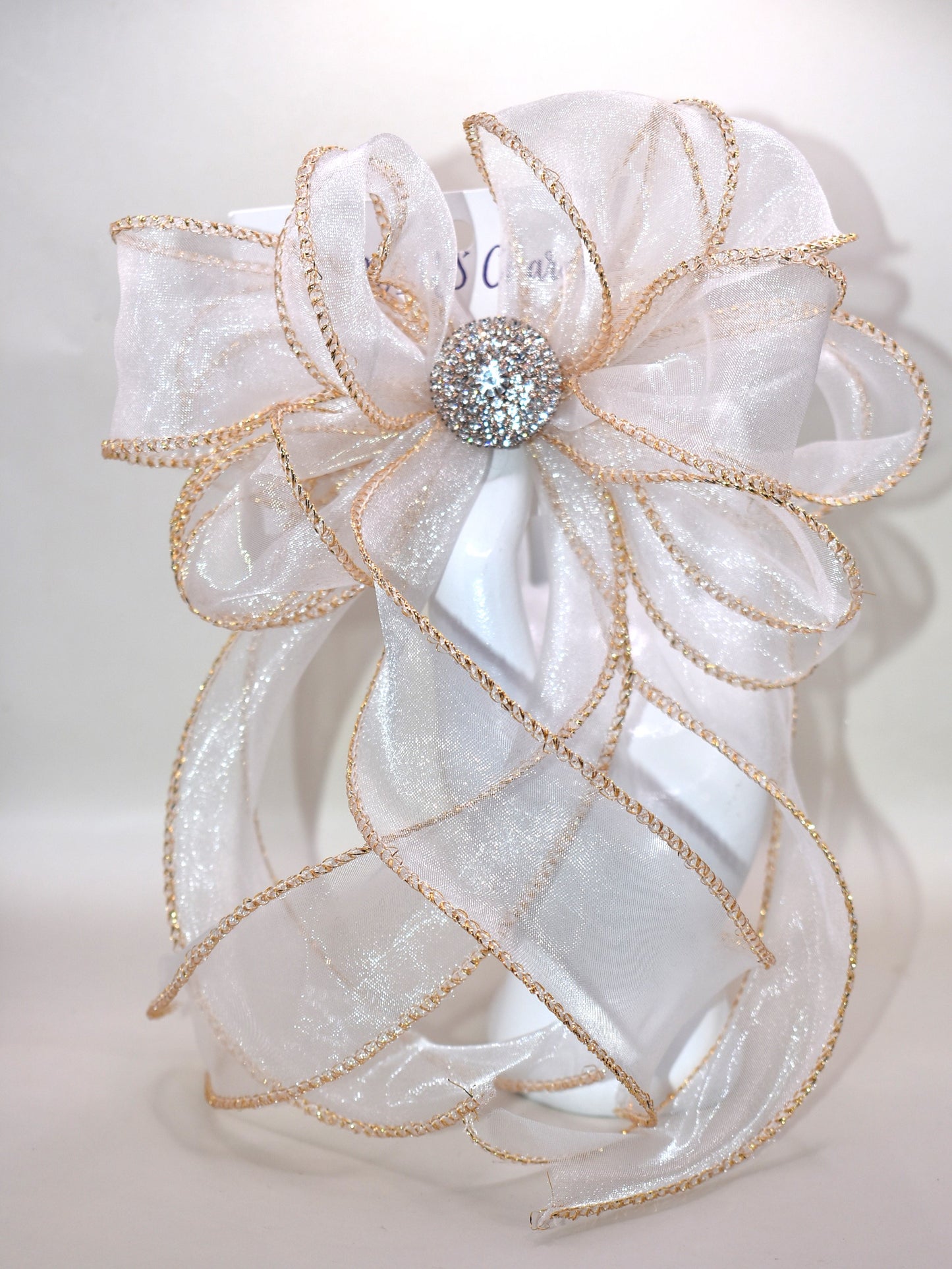 This gorgeous sheer long bow features graceful gold edging and a sparkling gold crystal charm that completes its refined look. Designed for all ages, it combines timeless elegance with practicality, thanks to the wrapped alligator clip for easy wear. A beautiful accessory that will quickly become a beloved favorite.