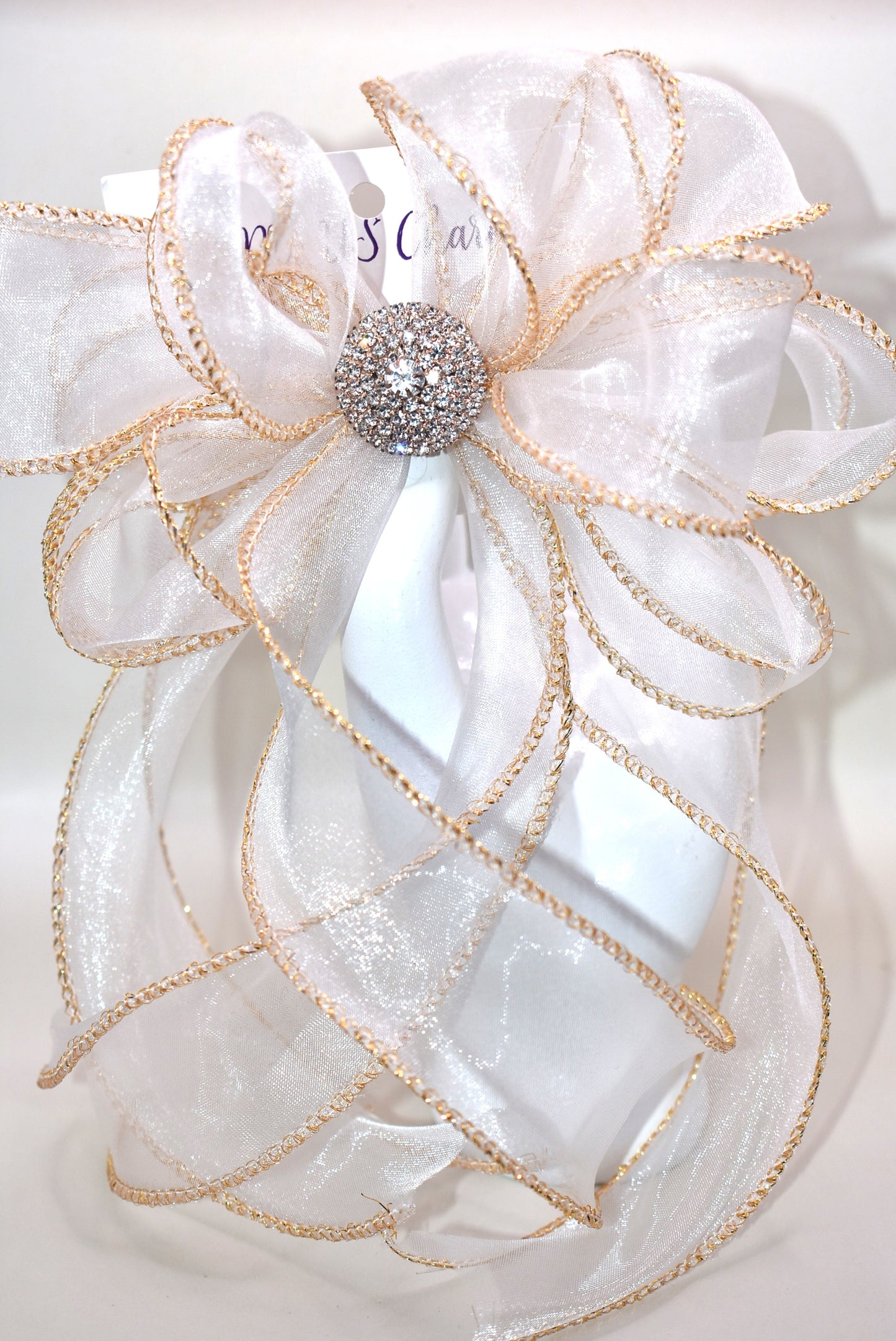 This gorgeous sheer long bow features graceful gold edging and a sparkling gold crystal charm that completes its refined look. Designed for all ages, it combines timeless elegance with practicality, thanks to the wrapped alligator clip for easy wear. A beautiful accessory that will quickly become a beloved favorite.