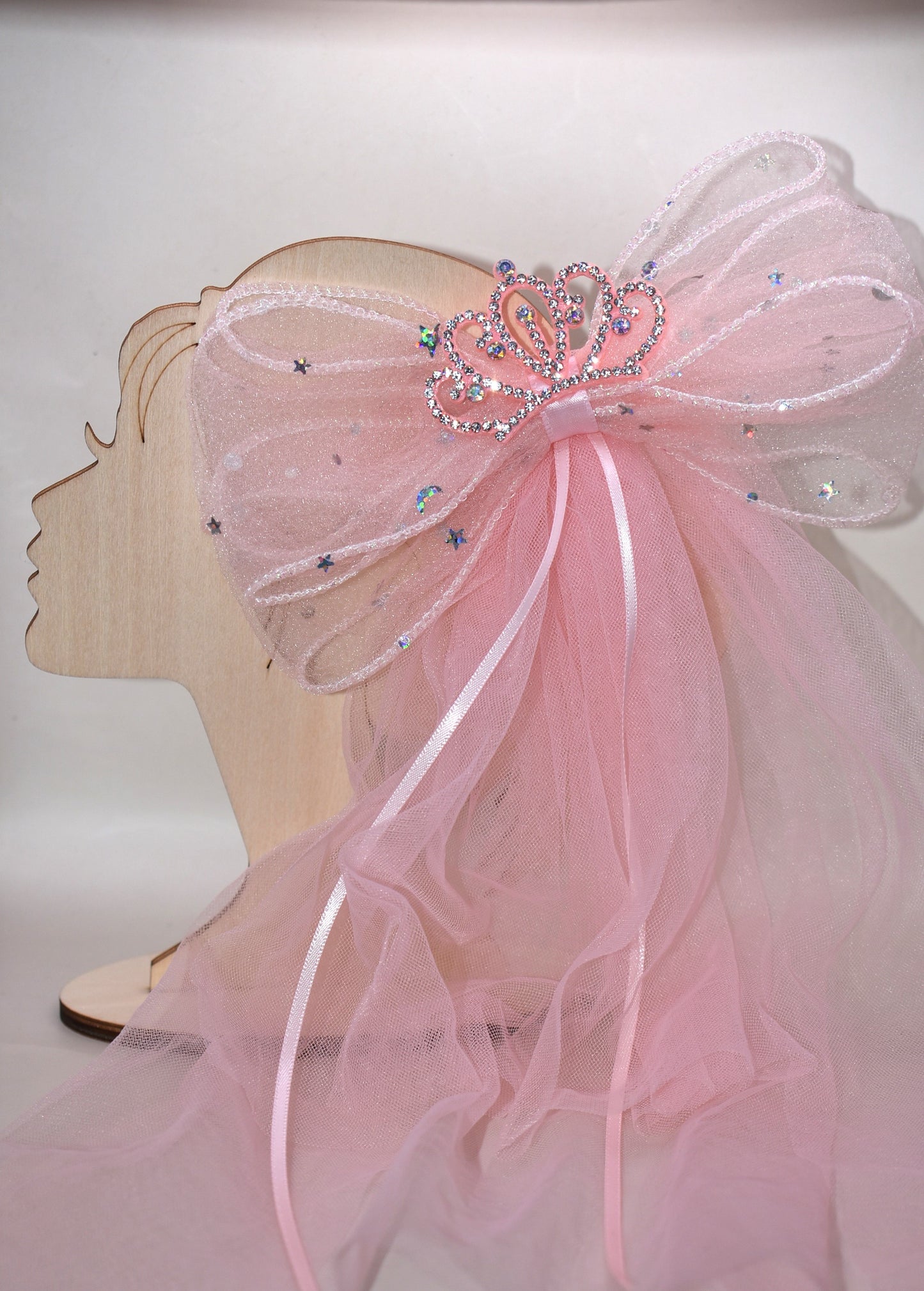 Add a touch of royalty with the Long Tail Collection 6 bow. Featuring a charming crown jewel perched atop layers of soft, flowing tulle, this easy clip-on accessory is perfect for anyone dreaming of a princess-worthy look. Effortlessly elevate any outfit with a playful sparkle that delights both kids and adults alike.