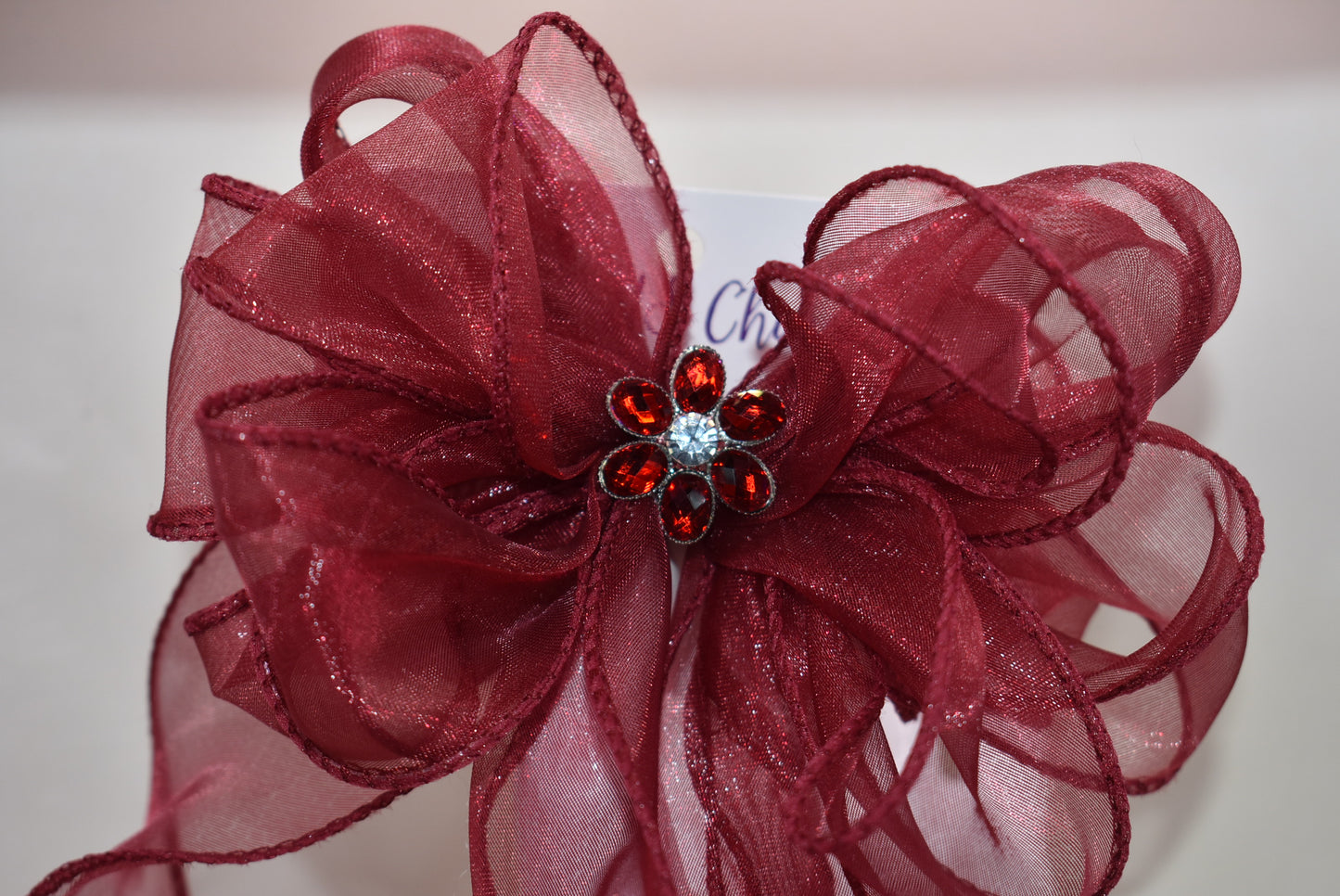 Elevate your ensemble with this elegant long burgundy bow from the Long Tail Collection. Featuring a refined fish tail ribbon design and a sparkling gem centerpiece, it adds a touch of sophistication to any outfit. Securely fastened with a wrapped alligator clip, this accessory combines style and practicality effortlessly.