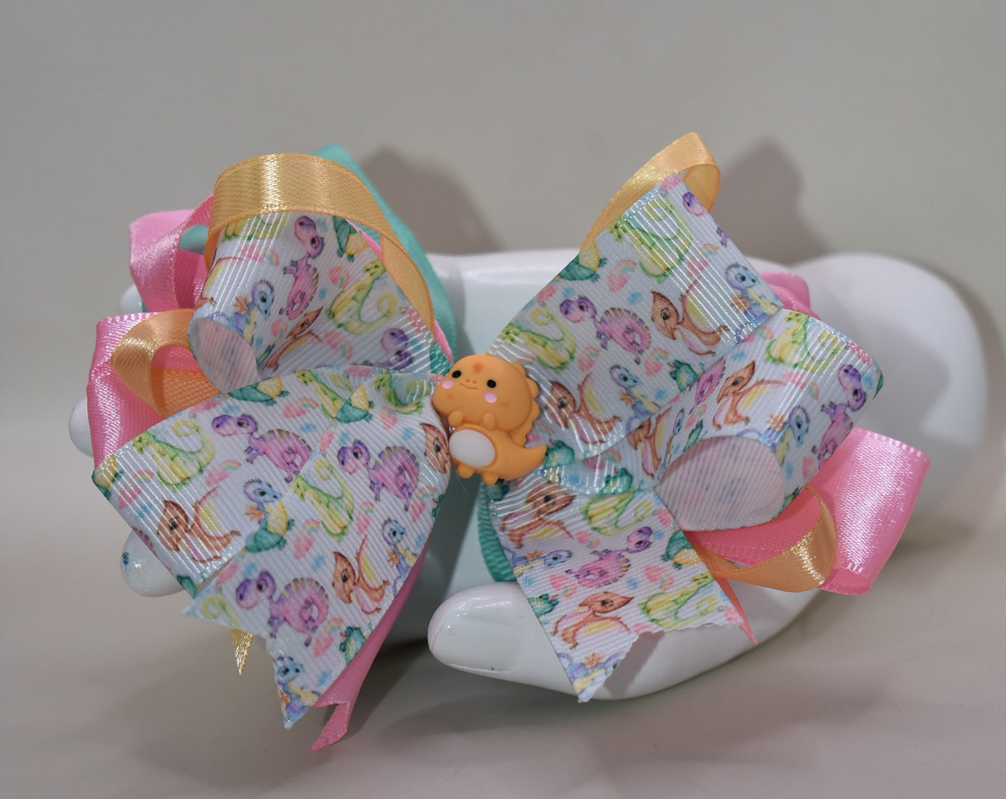 🦕 Roar into style with this absolutely adorable dinosaur charm! This cute little dino is tied up in a pretty multicolored ribbon bow that's ready to add a splash of fun to any outfit. Whether you're a dinosaur enthusiast or just love quirky accessories, this playful piece from Nana's Collection is the perfect way to show off your wild side. 🎀✨ Attach it to your favorite bag, keychain, or outfit for an instant charm boost that'll have everyone asking where you found such a delightful treasure!