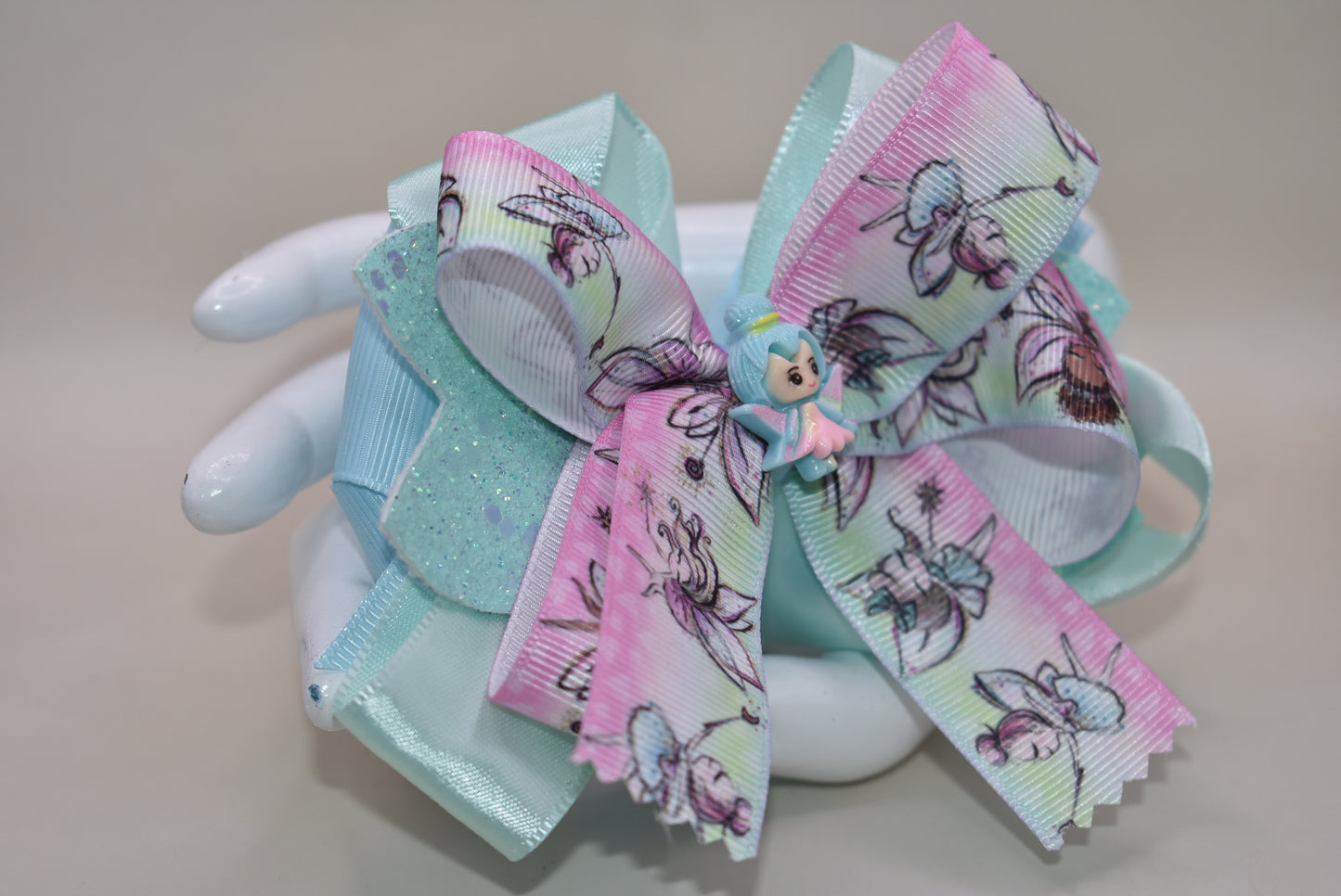 Introducing Nana's Collection 29: the perfect fairy bow that adds sparkle and layers of beautiful ribbon to any outfit. Its cute little fairy charm on top completes the adorable look. With a comfortable wrapped alligator clip, it's a must-have for any little girl's accessory collection!