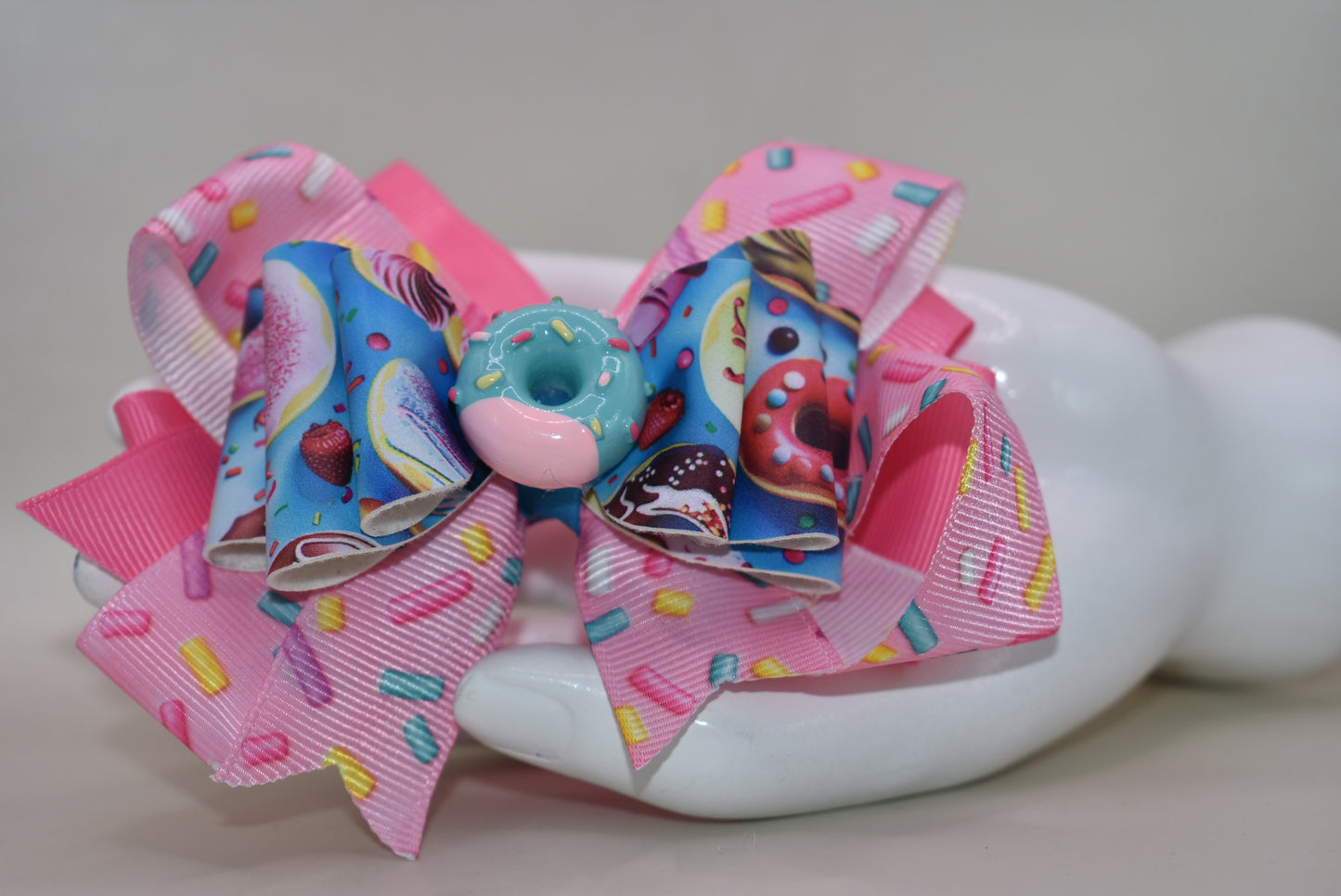 🍩 Get ready to sprinkle some sweetness into your style! This fun and colorful donut bow features layers of soft ribbon and faux leather that come together in the most adorable way. Topped with a charming donut charm, it's the perfect accessory to add a playful pop to any outfit. Whether you're dressing up for a special occasion or just want to brighten your everyday look, this delightful bow brings joy and personality to your wardrobe. 🎀✨