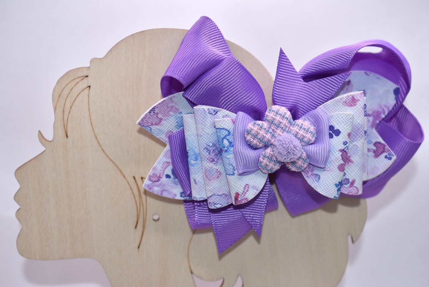 Elevate your bow game with this charming purple creation! 💜 Featuring a delightful floral design layered with rich purple ribbons, this bow brings instant personality to any hairstyle. The adorable purple flower topped with a fluffy pom pom adds that extra touch of whimsy. ✨ Wrapped in a secure alligator clip, it stays put all day long, so you can play, explore, and have fun without worry. Perfect for spring adventures! 🌸