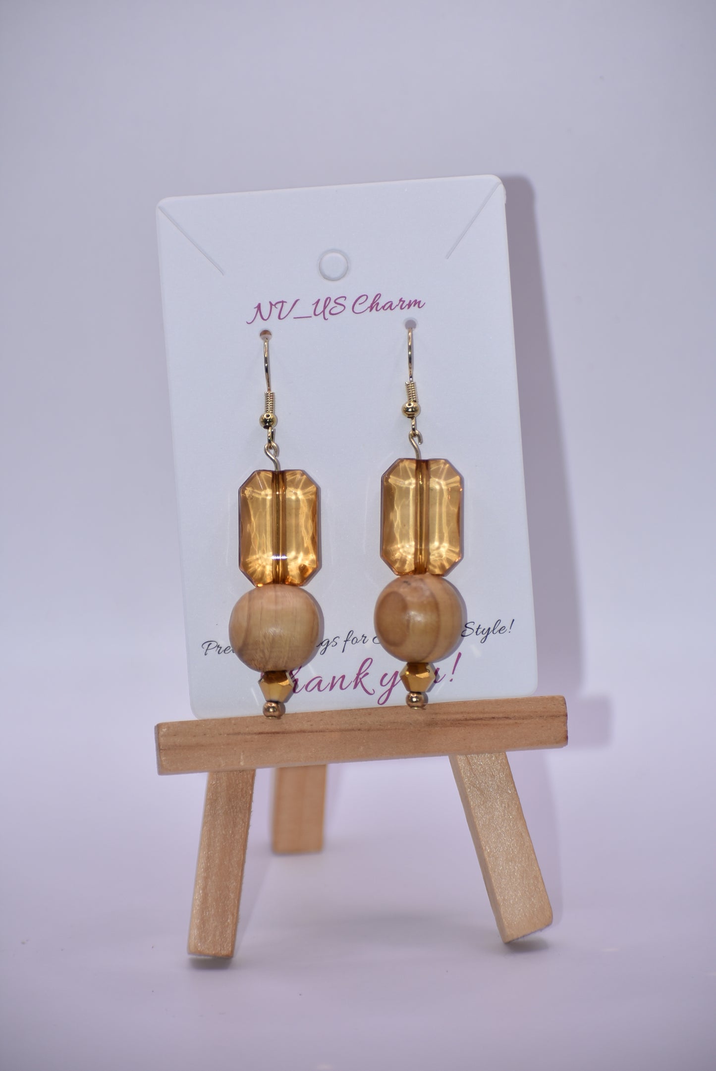 Add some playful charm to your outfit with these gold hypoallergenic hook earrings. Featuring an amber gem with a round wood bead and small beading at the bottom, they are perfect for dressing up or down. A must-have addition to any wardrobe!