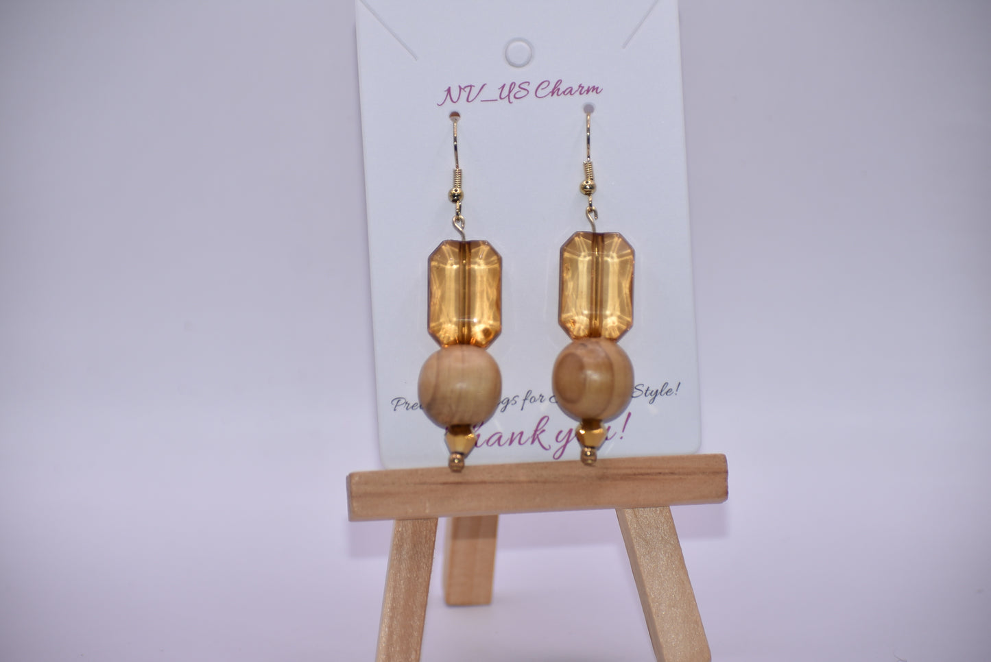 Add some playful charm to your outfit with these gold hypoallergenic hook earrings. Featuring an amber gem with a round wood bead and small beading at the bottom, they are perfect for dressing up or down. A must-have addition to any wardrobe!