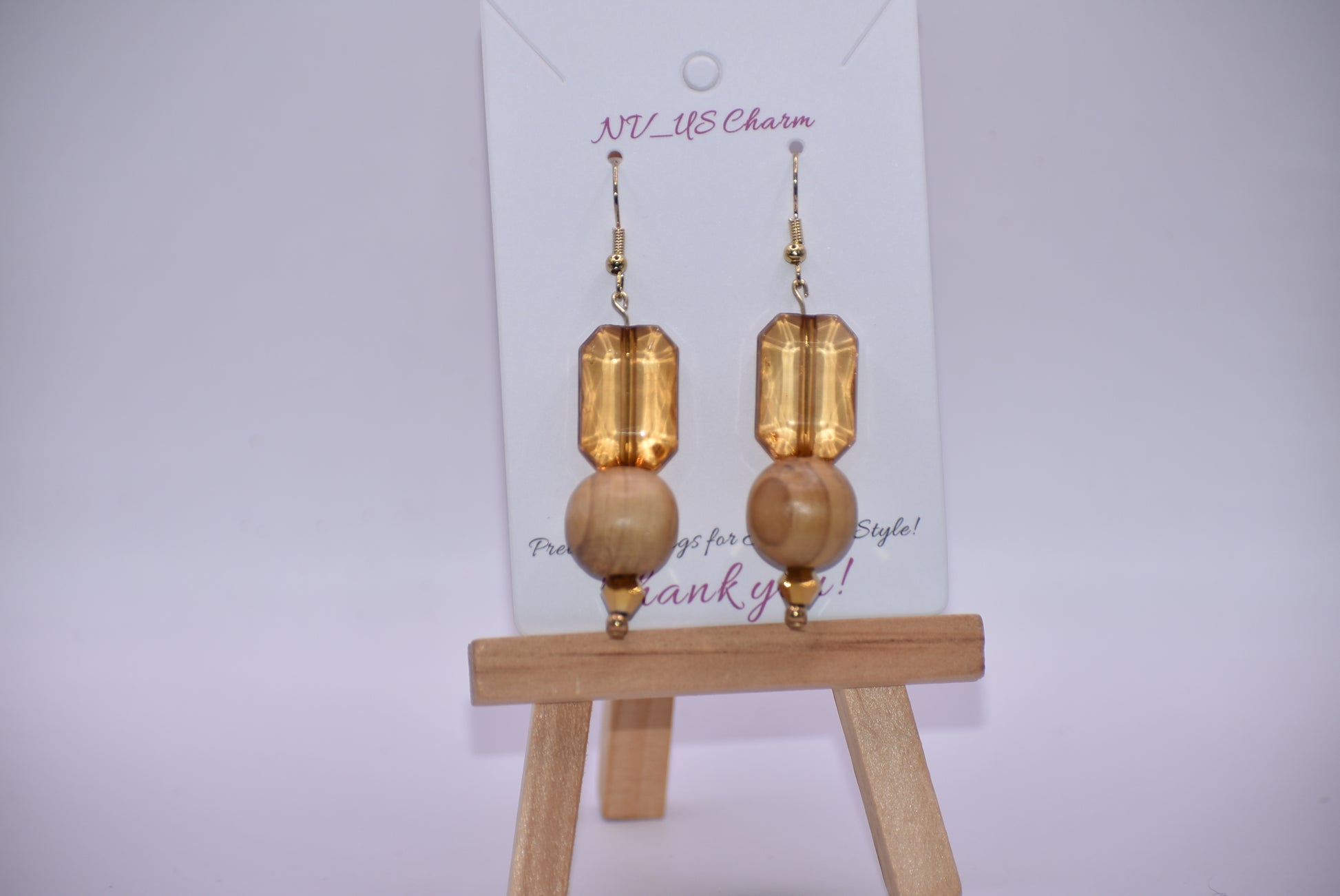 Add some playful charm to your outfit with these gold hypoallergenic hook earrings. Featuring an amber gem with a round wood bead and small beading at the bottom, they are perfect for dressing up or down. A must-have addition to any wardrobe!