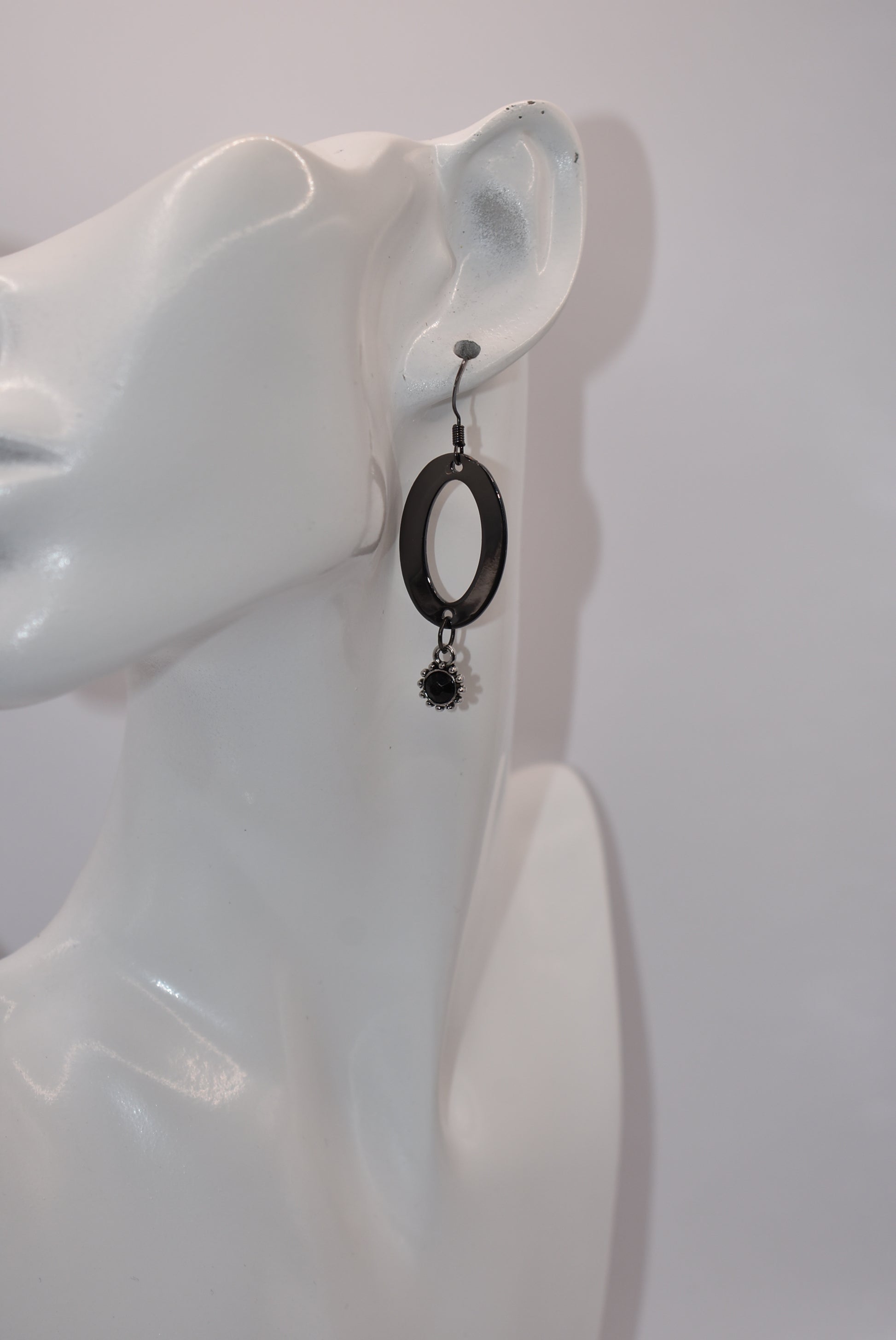 "Sleek, stylish, and hypoallergenic, our Black Collection features black hooks that hold a polished black oval shaped piece with a stunning silver/black charm and center stone hanging from the bottom.  Perfect for adding a touch of edgy elegance to any outfit. (Definitely not your average black jewelry.)"