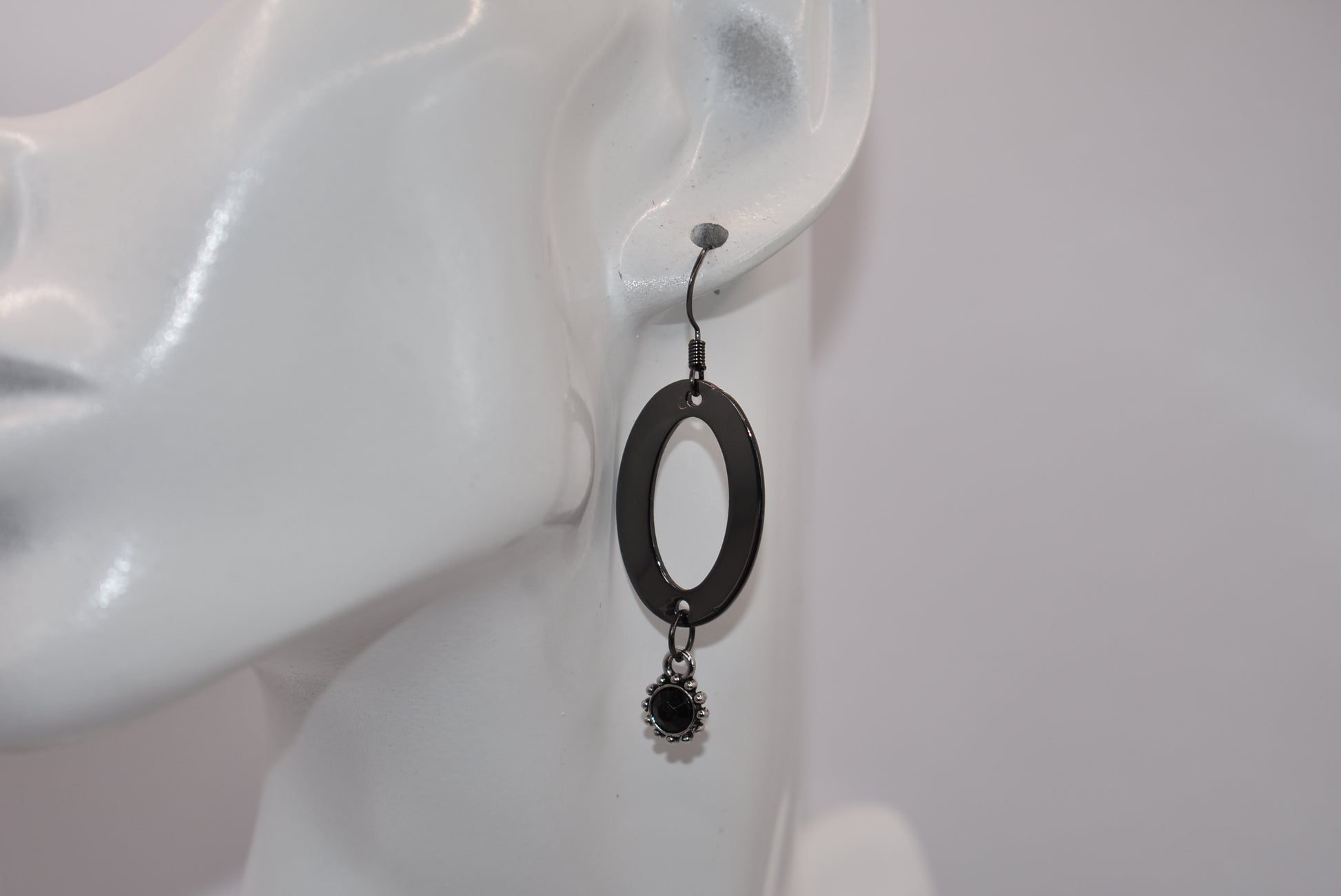 "Sleek, stylish, and hypoallergenic, our Black Collection features black hooks that hold a polished black oval shaped piece with a stunning silver/black charm and center stone hanging from the bottom.  Perfect for adding a touch of edgy elegance to any outfit. (Definitely not your average black jewelry.)"