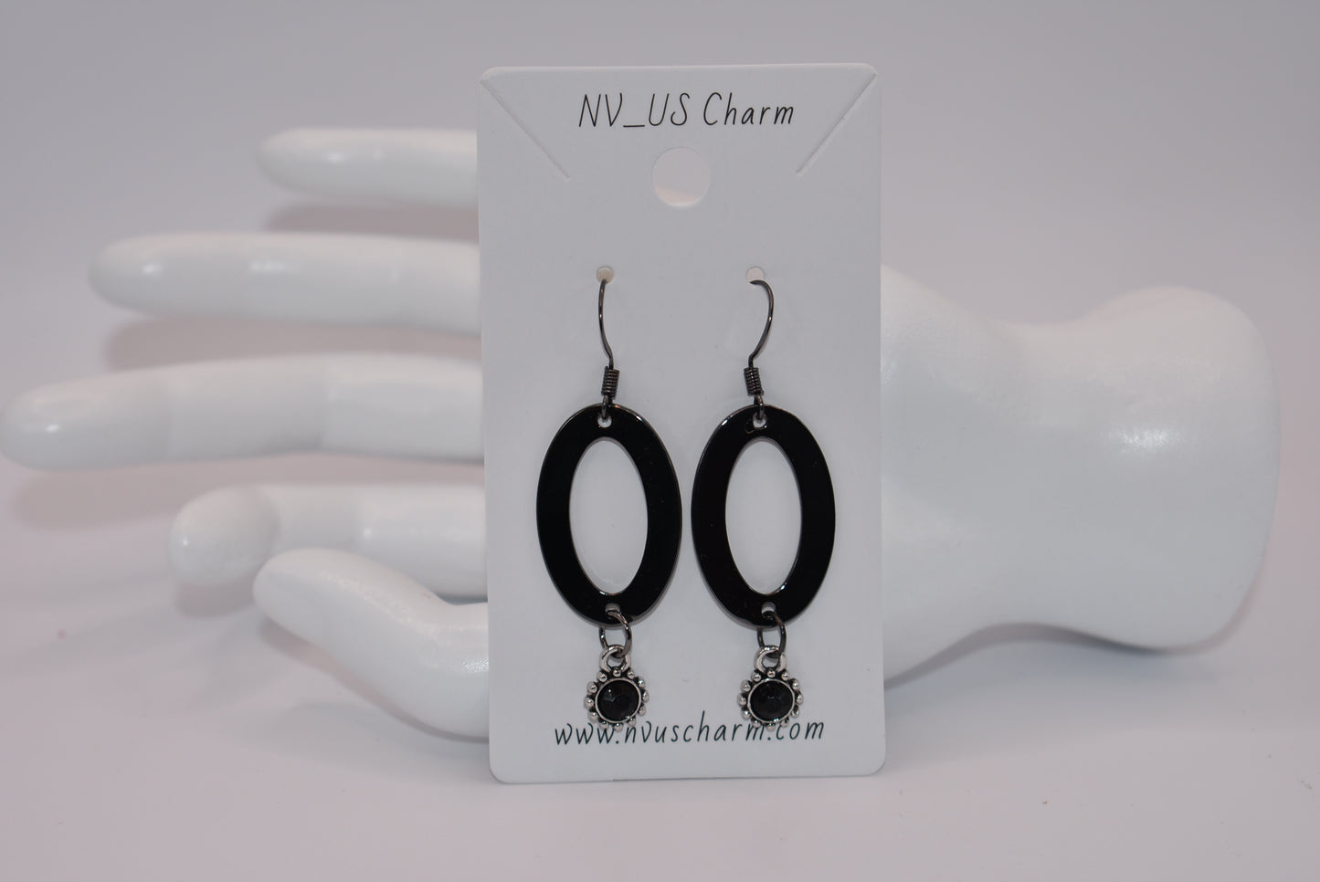 "Sleek, stylish, and hypoallergenic, our Black Collection features black hooks that hold a polished black oval shaped piece with a stunning silver/black charm and center stone hanging from the bottom.  Perfect for adding a touch of edgy elegance to any outfit. (Definitely not your average black jewelry.)"