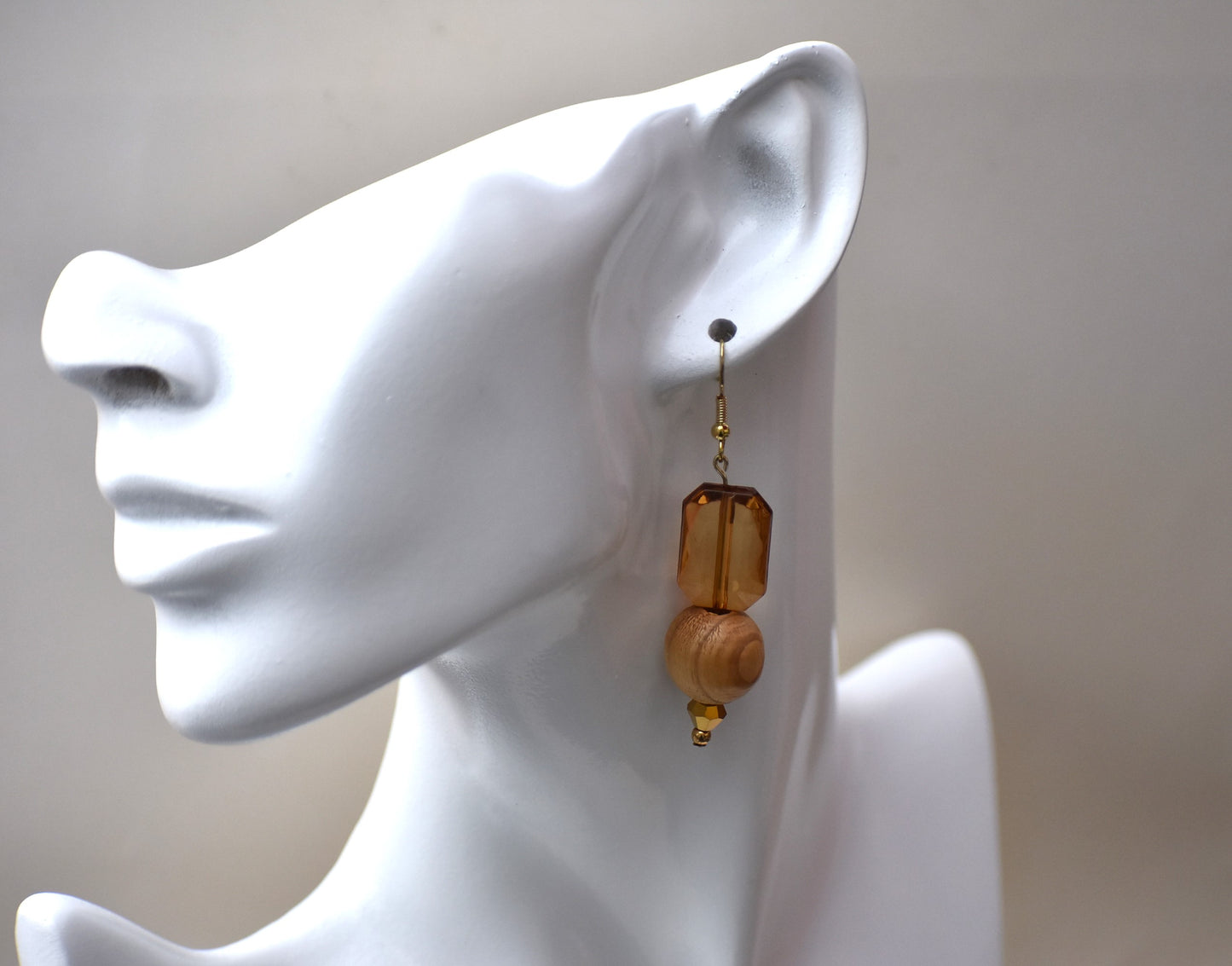 Add some playful charm to your outfit with these gold hypoallergenic hook earrings. Featuring an amber gem with a round wood bead and small beading at the bottom, they are perfect for dressing up or down. A must-have addition to any wardrobe!