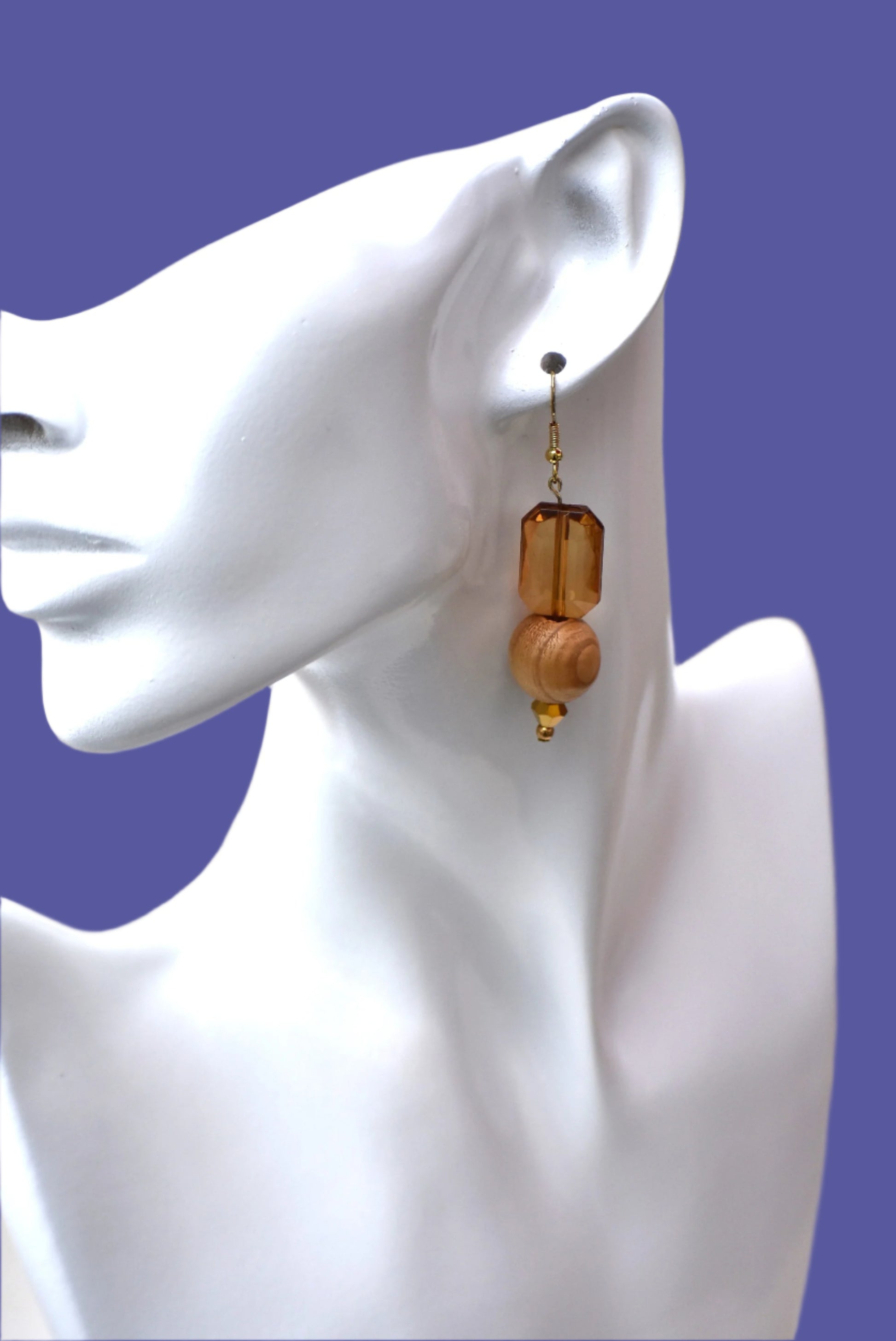 Add some playful charm to your outfit with these gold hypoallergenic hook earrings. Featuring an amber gem with a round wood bead and small beading at the bottom, they are perfect for dressing up or down. A must-have addition to any wardrobe!