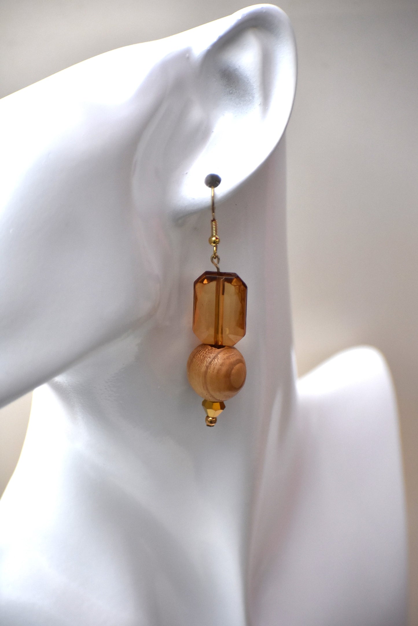 Add some playful charm to your outfit with these gold hypoallergenic hook earrings. Featuring an amber gem with a round wood bead and small beading at the bottom, they are perfect for dressing up or down. A must-have addition to any wardrobe!