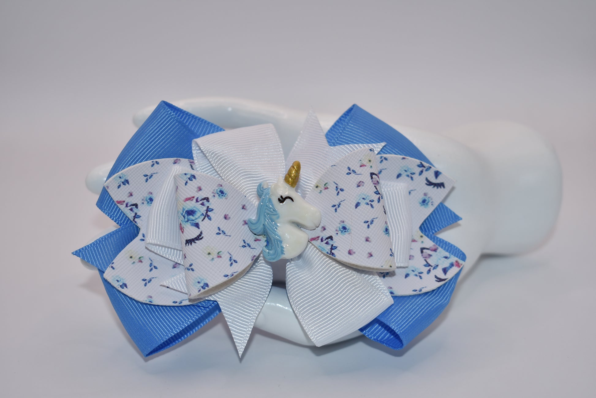 Unleash your little girl's imagination with Nana's Collection! Our Pretty Unicorn motif, made with a mix of blue and white ribbon and luxe faux leather, will have her feeling magical. With this bow, she'll be sure to fall in love with accessorizing (and maybe even unicorns)!