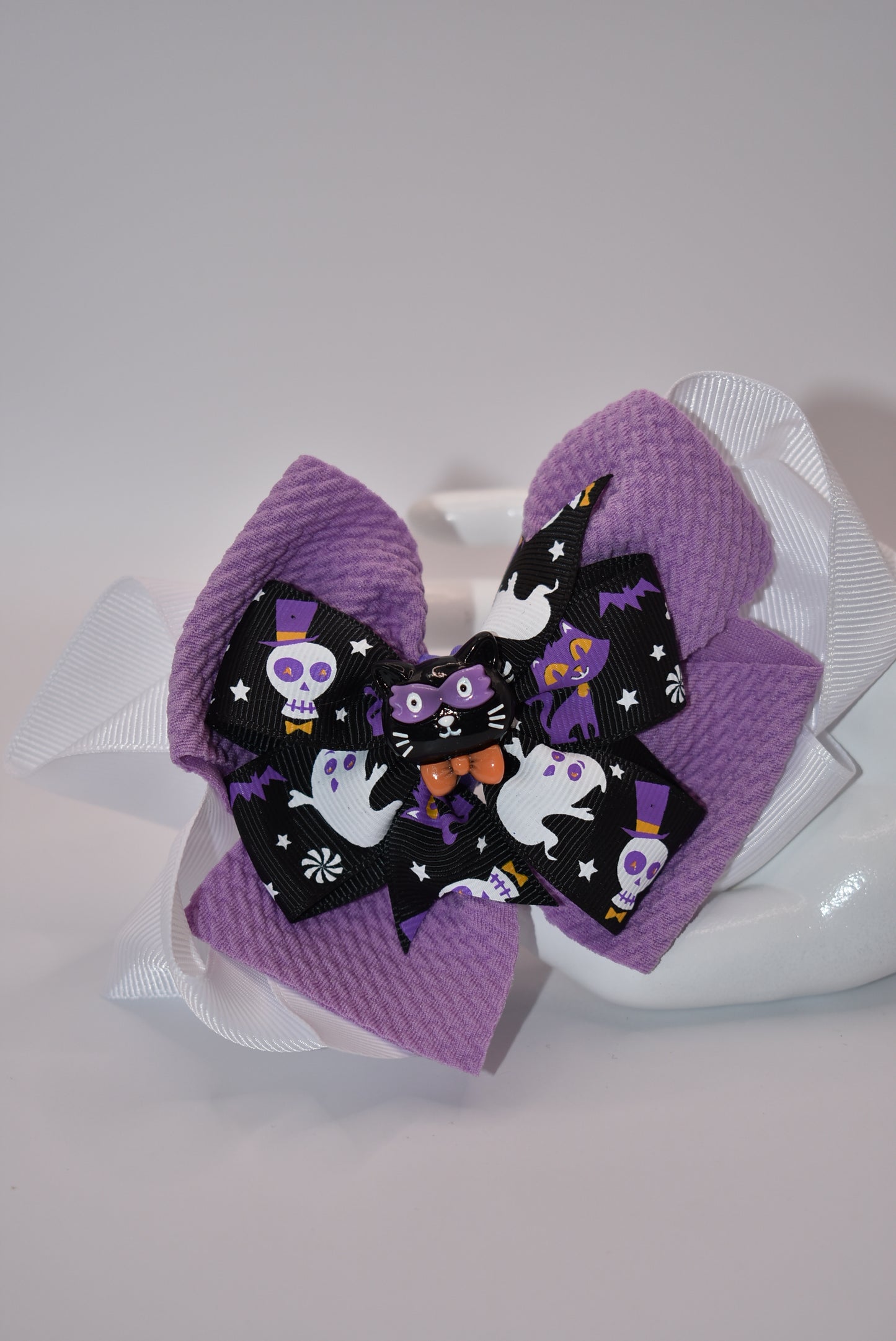 Spook up your Halloween outfit with Nana's Collection's black and purple bow! With an alligator clip for easy styling, you'll be the center of attention as "ghosts and goblins come on out" (wink wink).