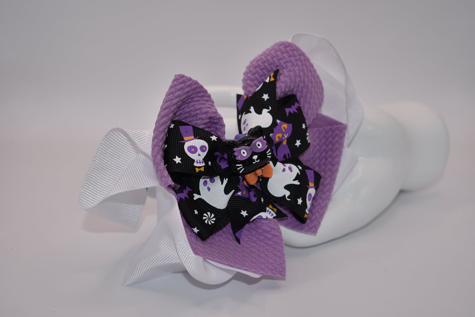 Spook up your Halloween outfit with Nana's Collection's black and purple bow! With an alligator clip for easy styling, you'll be the center of attention as "ghosts and goblins come on out" (wink wink).