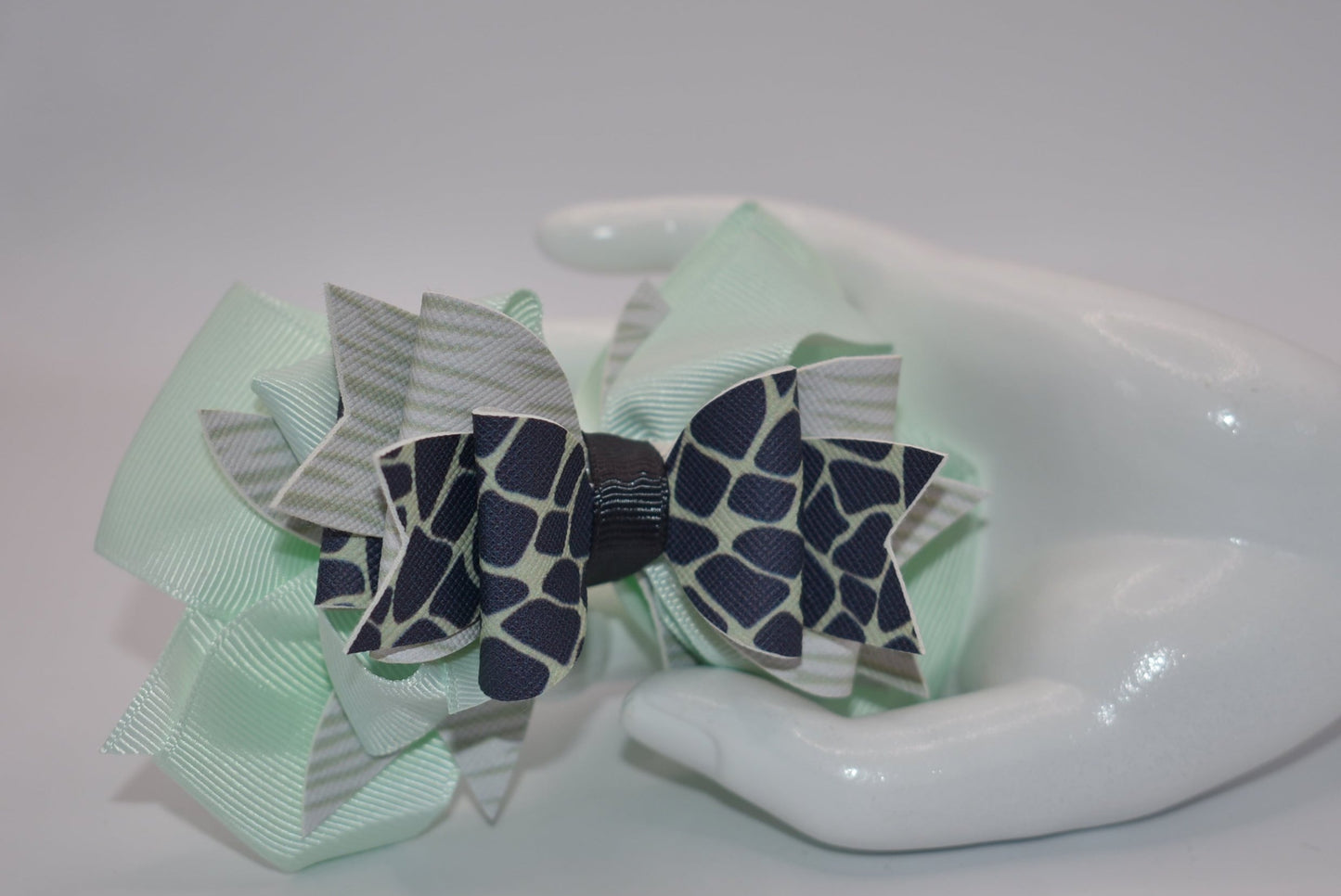 Nana's Collection is the perfect addition to your little one's wardrobe! This Super fun bow features a unique green and dark blue pattern, adding a touch of playfulness to any outfit. The alligator clip makes for easy wear, while the soft ribbon and faux leather provide the perfect blend of comfort and style.