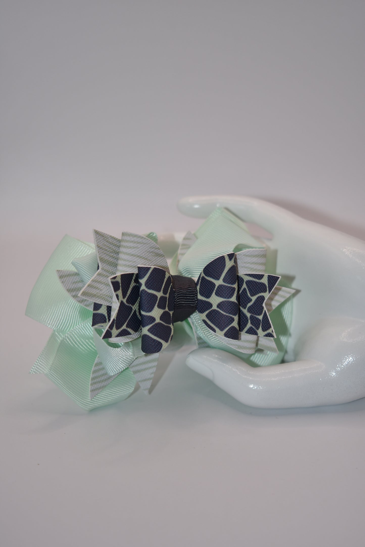 Nana's Collection is the perfect addition to your little one's wardrobe! This Super fun bow features a unique green and dark blue pattern, adding a touch of playfulness to any outfit. The alligator clip makes for easy wear, while the soft ribbon and faux leather provide the perfect blend of comfort and style.