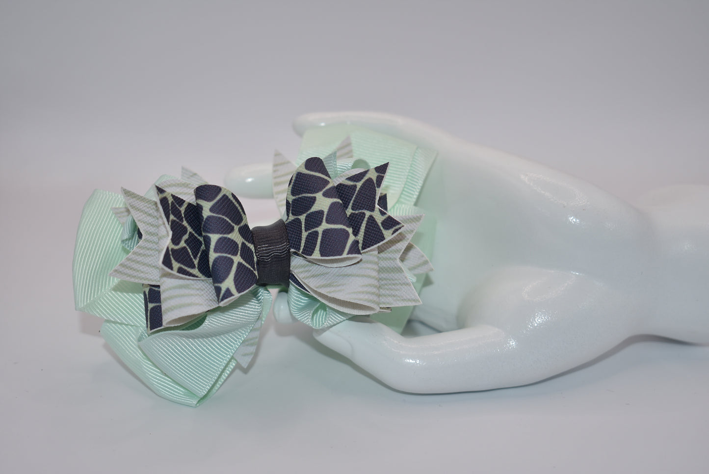 Nana's Collection is the perfect addition to your little one's wardrobe! This Super fun bow features a unique green and dark blue pattern, adding a touch of playfulness to any outfit. The alligator clip makes for easy wear, while the soft ribbon and faux leather provide the perfect blend of comfort and style.