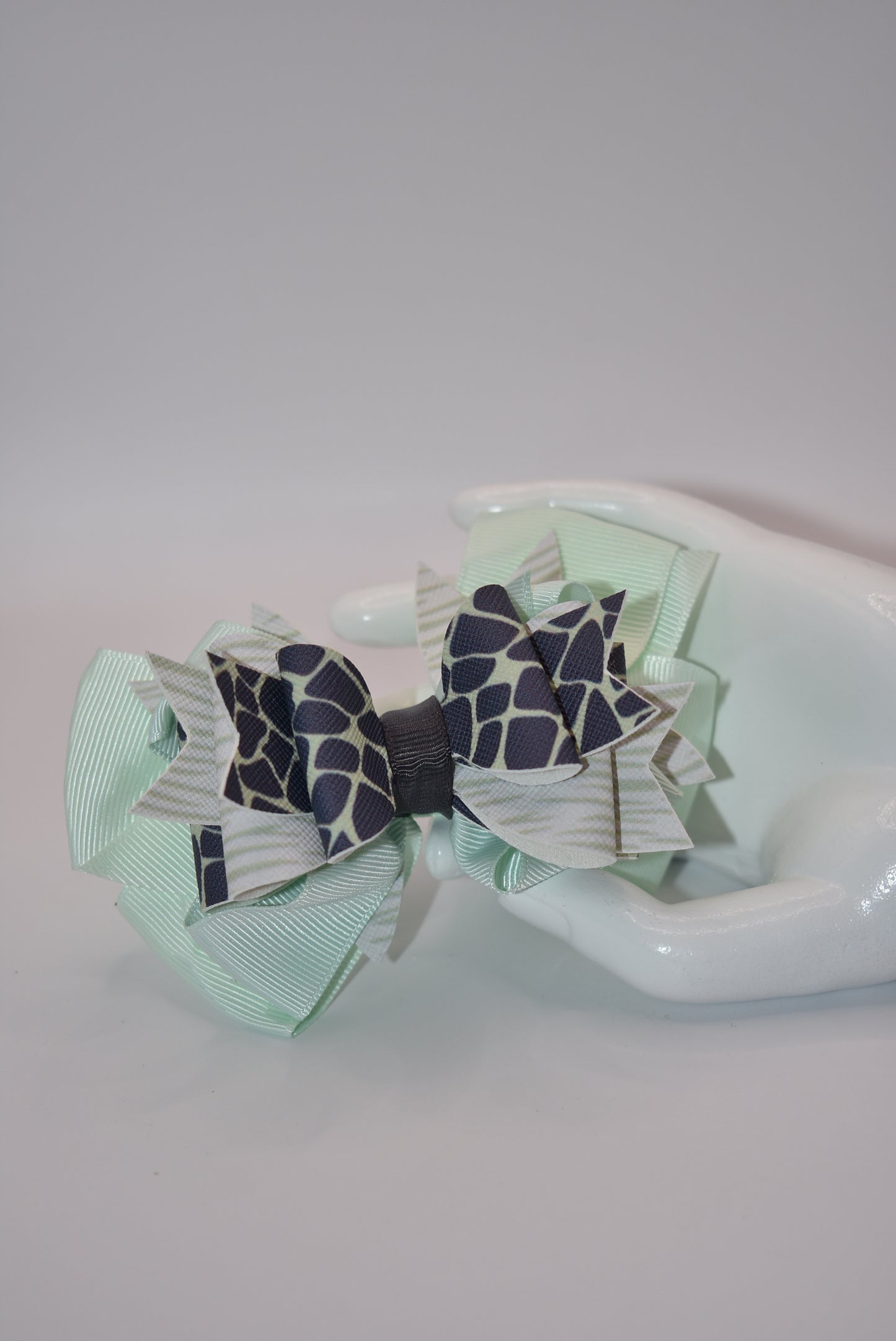 Nana's Collection is the perfect addition to your little one's wardrobe! This Super fun bow features a unique green and dark blue pattern, adding a touch of playfulness to any outfit. The alligator clip makes for easy wear, while the soft ribbon and faux leather provide the perfect blend of comfort and style.