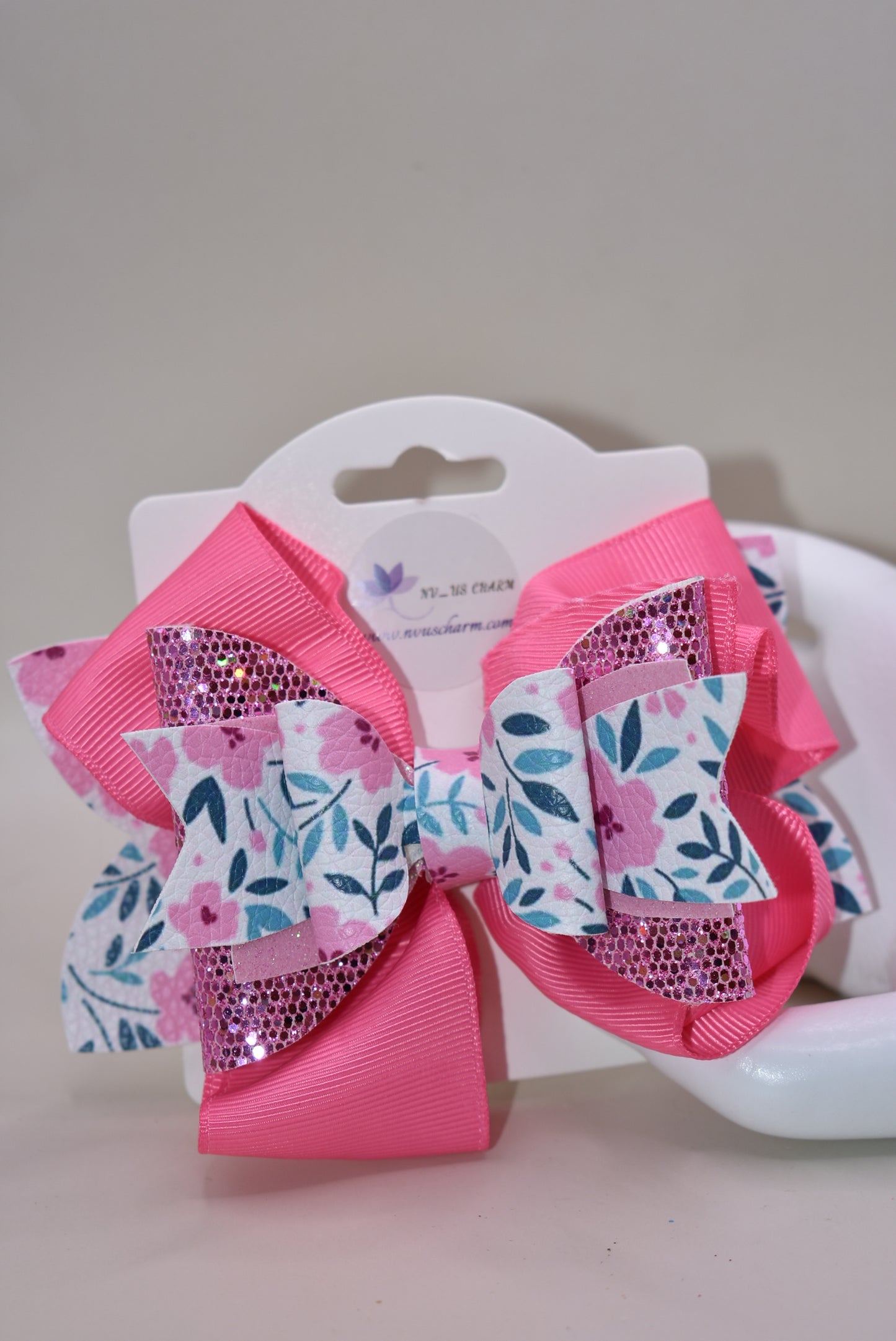 The Bow Corner is a must-have accessory for any little girl! The beautiful 4" pink bow, with its mix of ribbon, glitter, and faux leather, adds a touch of charm to any outfit. The unique flower pattern and covered alligator clip make it both comfortable and easy to wear. (Your little one will look so cute you'll pinkie-swear it!)
