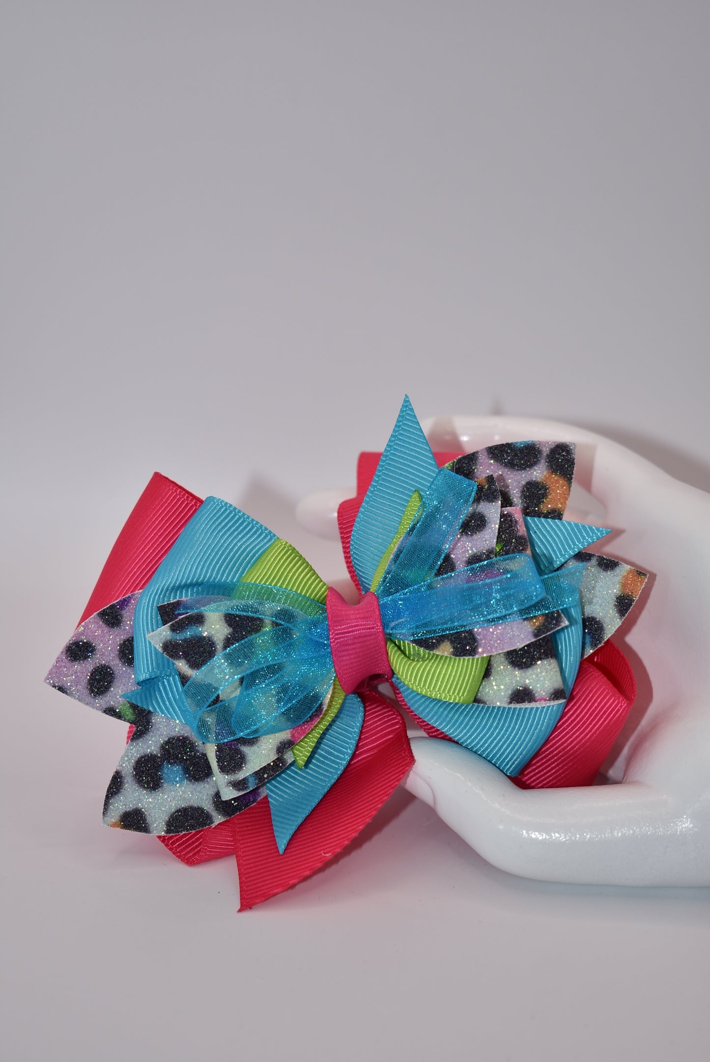 Unleash your wild side with Nana's Collection! Our crazy fun leopard print multi-colored bow is like all your favorite colors rolled into one. Made with faux leather and soft ribbon, this bow is fierce yet stylish. Secured with an alligator clip, it's the perfect accessory for any outfit. Go wild with Nana's Collection!