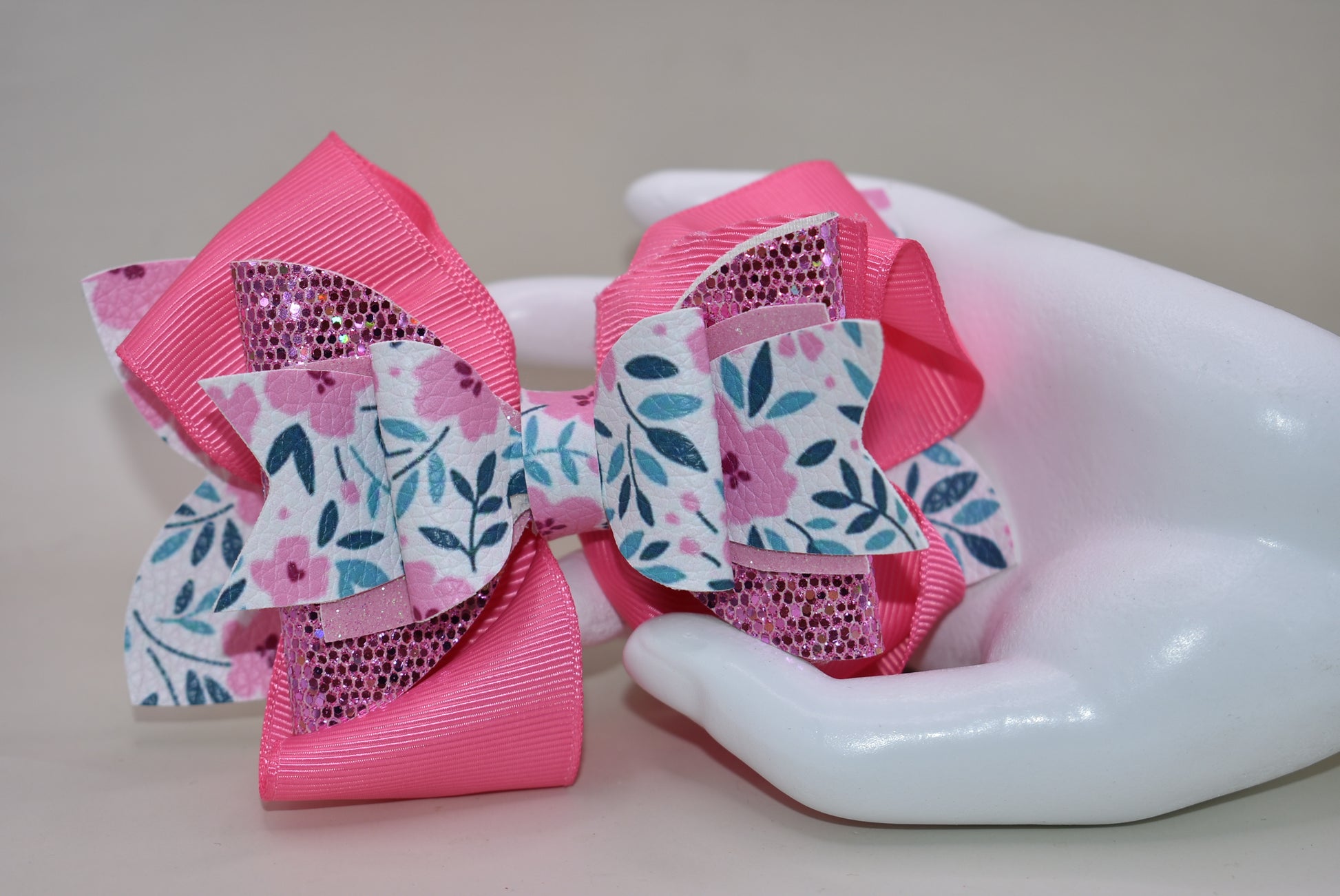 The Bow Corner is a must-have accessory for any little girl! The beautiful 4" pink bow, with its mix of ribbon, glitter, and faux leather, adds a touch of charm to any outfit. The unique flower pattern and covered alligator clip make it both comfortable and easy to wear. (Your little one will look so cute you'll pinkie-swear it!)
