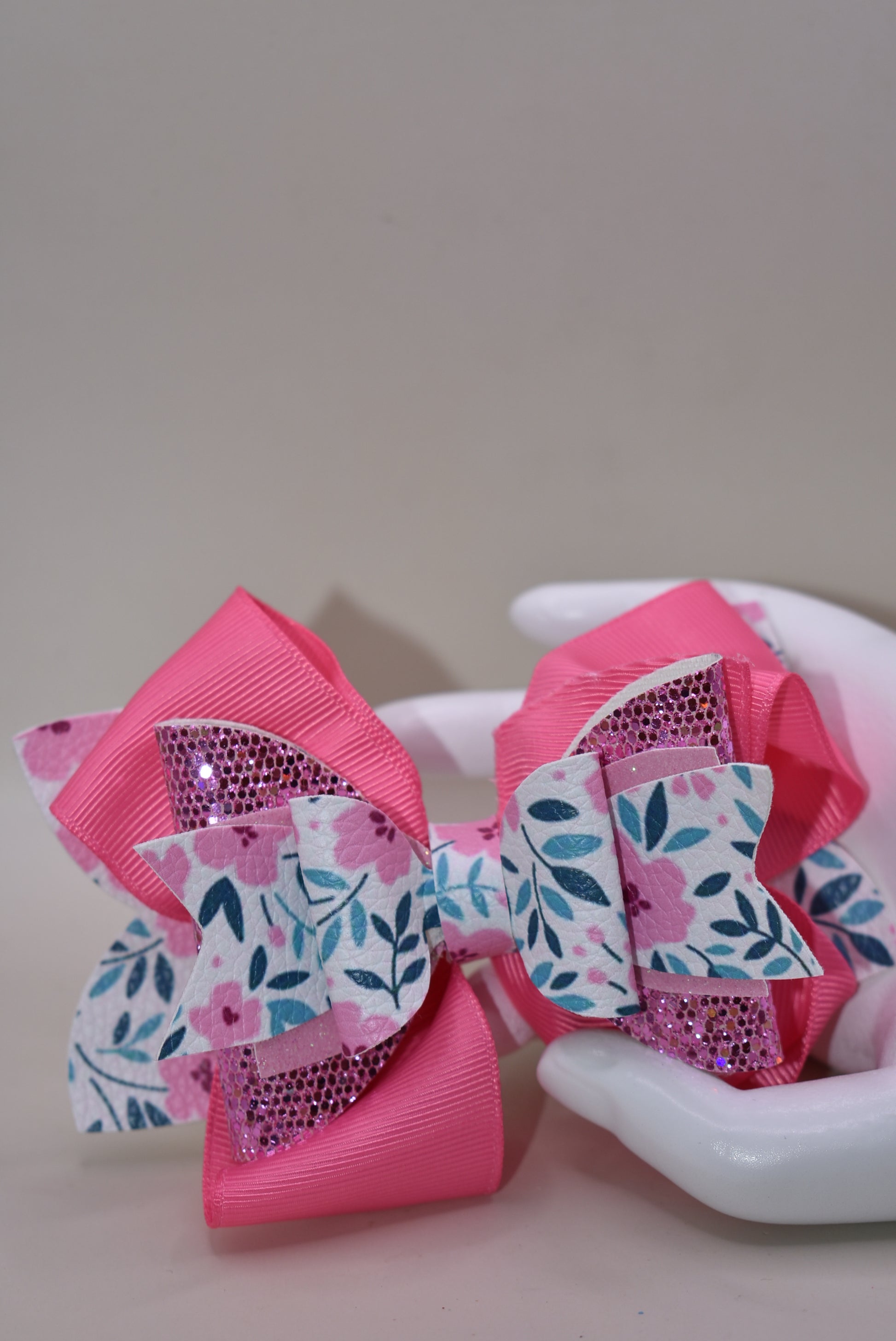 The Bow Corner is a must-have accessory for any little girl! The beautiful 4" pink bow, with its mix of ribbon, glitter, and faux leather, adds a touch of charm to any outfit. The unique flower pattern and covered alligator clip make it both comfortable and easy to wear. (Your little one will look so cute you'll pinkie-swear it!)