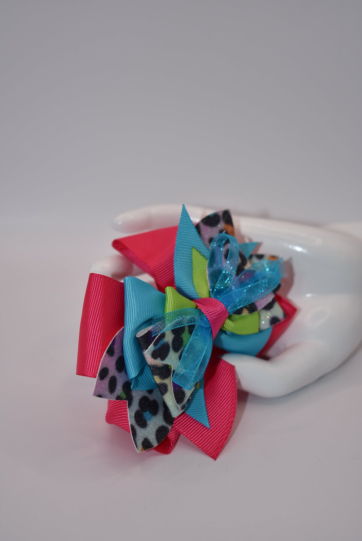 Unleash your wild side with Nana's Collection! Our crazy fun leopard print multi-colored bow is like all your favorite colors rolled into one. Made with faux leather and soft ribbon, this bow is fierce yet stylish. Secured with an alligator clip, it's the perfect accessory for any outfit. Go wild with Nana's Collection!