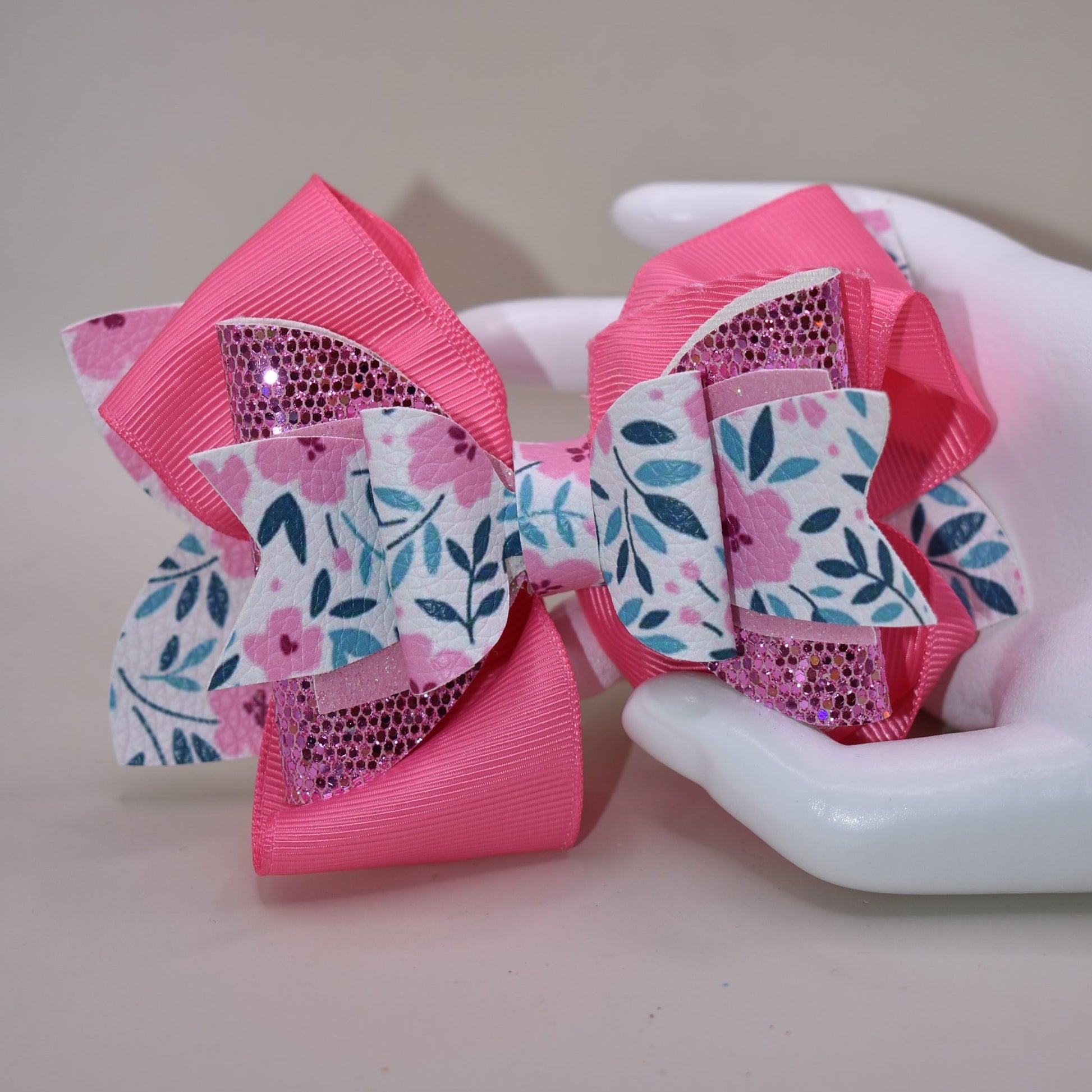 The Bow Corner is a must-have accessory for any little girl! The beautiful 4" pink bow, with its mix of ribbon, glitter, and faux leather, adds a touch of charm to any outfit. The unique flower pattern and covered alligator clip make it both comfortable and easy to wear. (Your little one will look so cute you'll pinkie-swear it!)